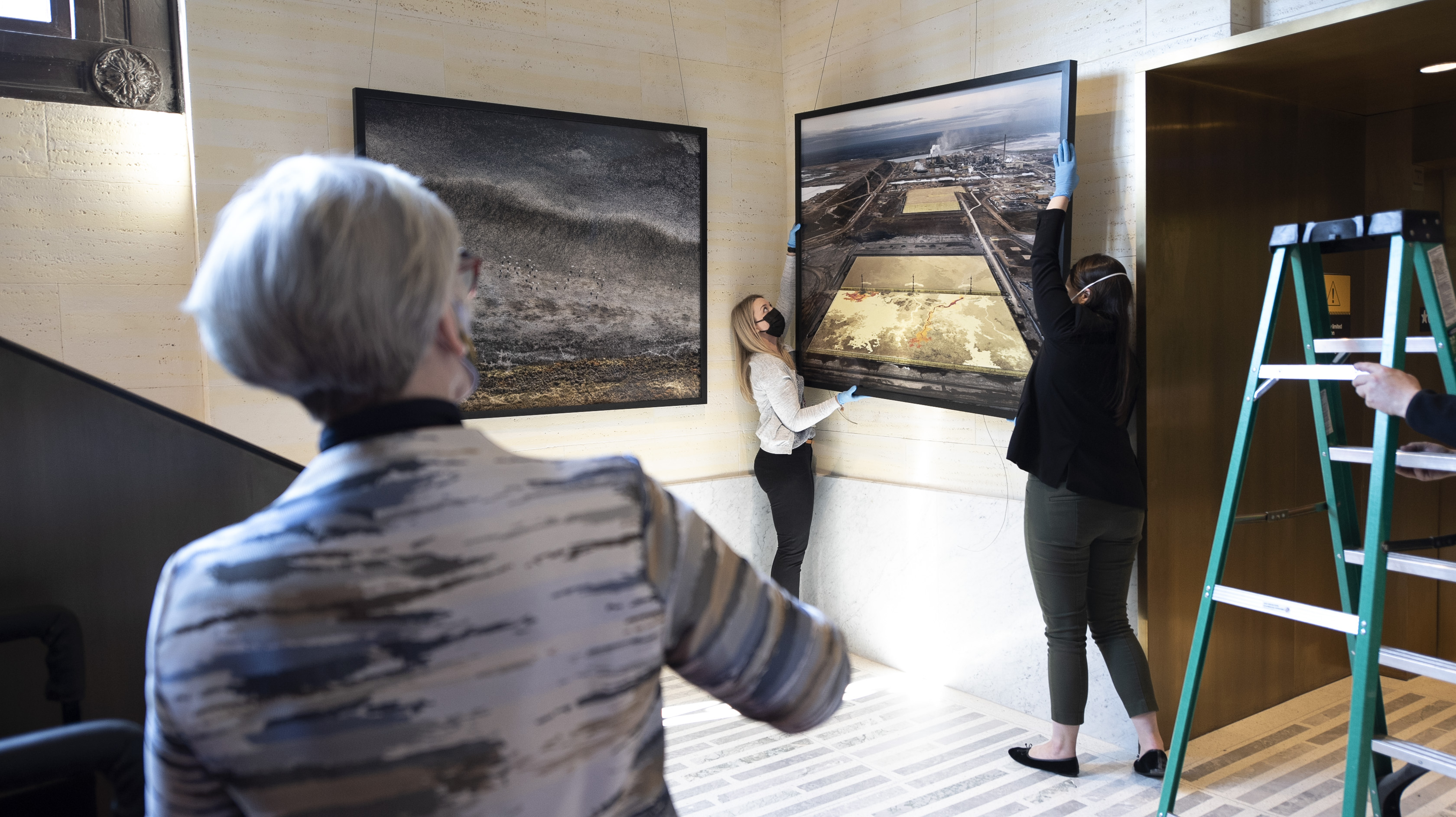 Senator Patricia Bovey (left) oversees the installation of the “Visual Voices: Artists & the Environment” exhibit in the Senate of Canada Building on April 28, 2022