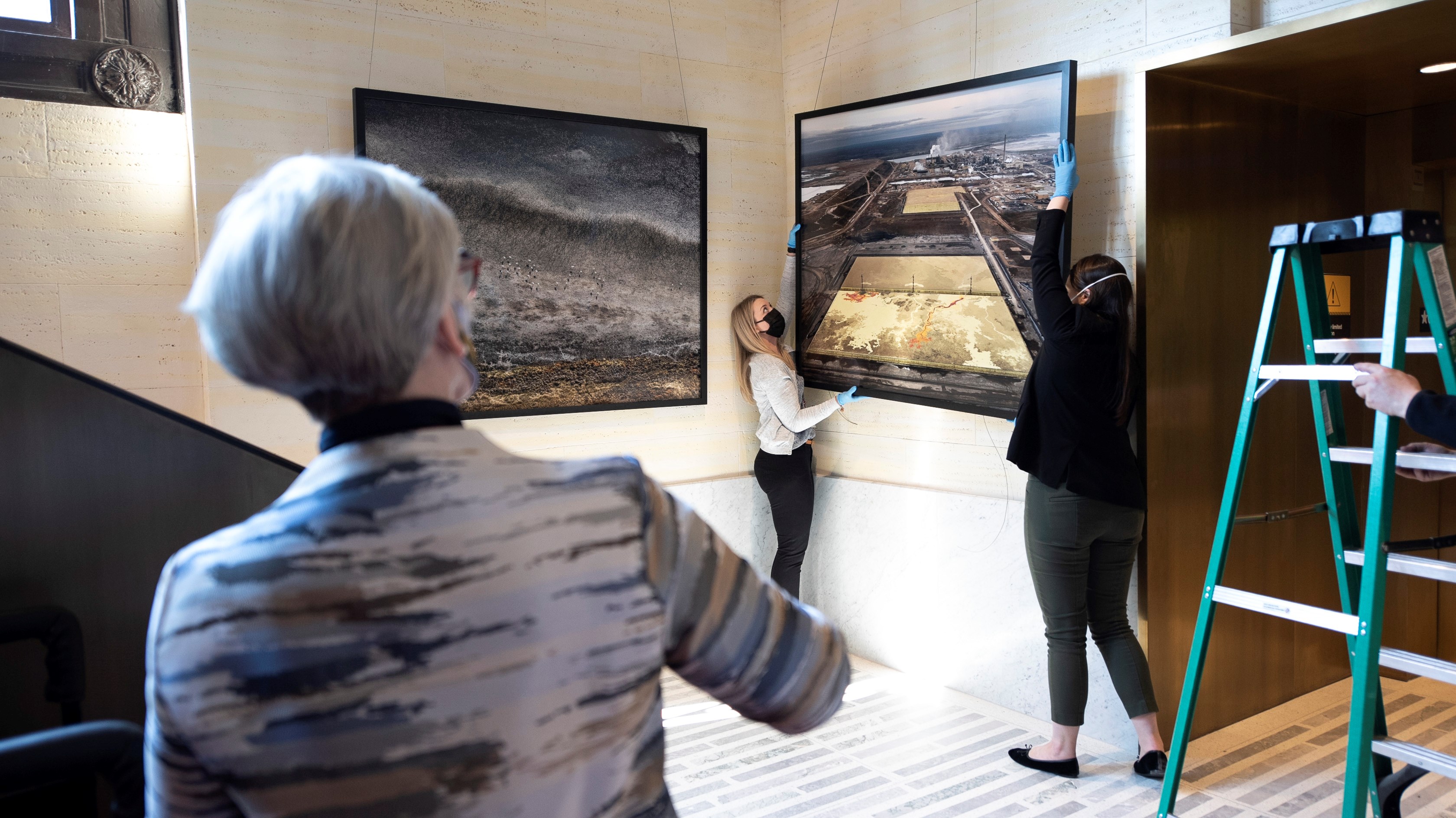 Senator Patricia Bovey (left) oversees the installation of the “Visual Voices: Artists & the Environment” exhibit in the Senate of Canada Building on April 28, 2022