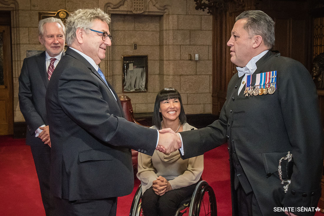 Senator Éric Forest, pictured being greeted by the Usher of the Black Rod, Senator Chantal Petitclerc, and Senator Peter Harder.