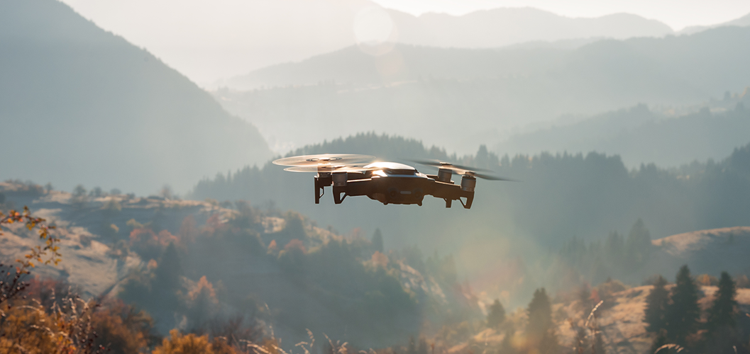 A small drone flying over countryside.