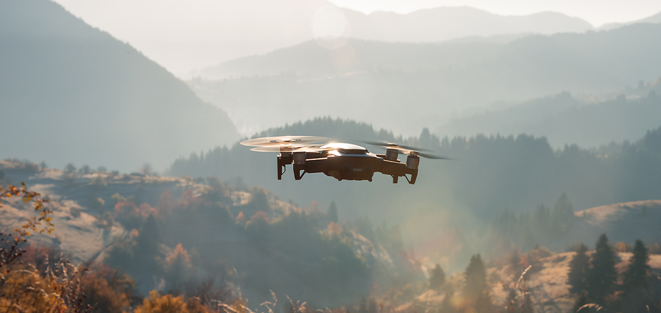 A small drone flying over countryside.