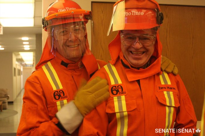 Le sénateur Paul Massicotte (à gauche) et le sénateur Denis Patterson enfilent de l’équipement de protection avant de visiter une d’aluminiumerie à Kitimat, en C-B.