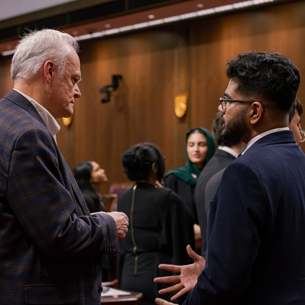 An older man and a younger one discuss in the Senate Chamber.