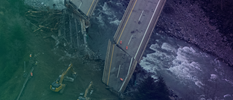 Aerial view of a construction site showcasing a partially collapsed bridge over a river.