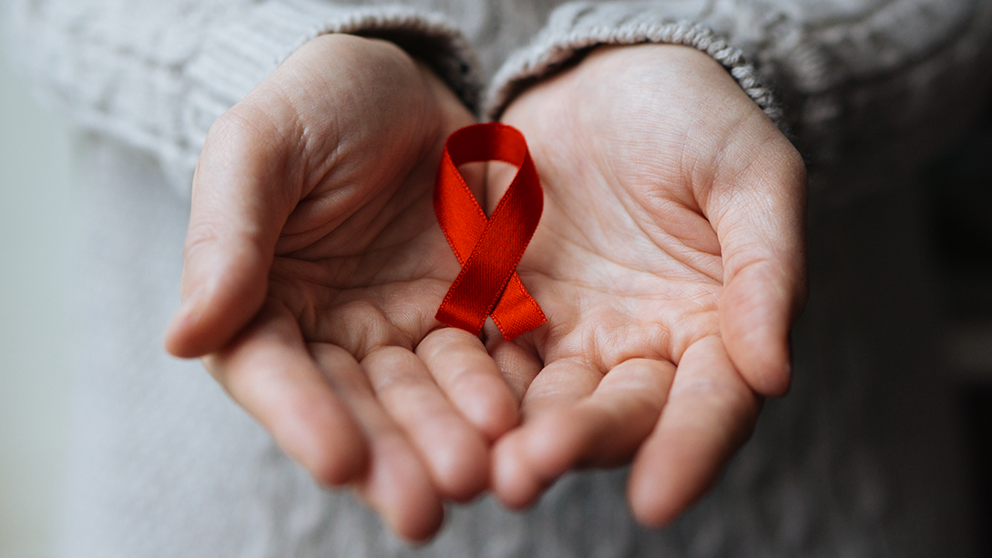 A red awareness ribbon in cupped hands.
