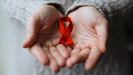 A red awareness ribbon in cupped hands.