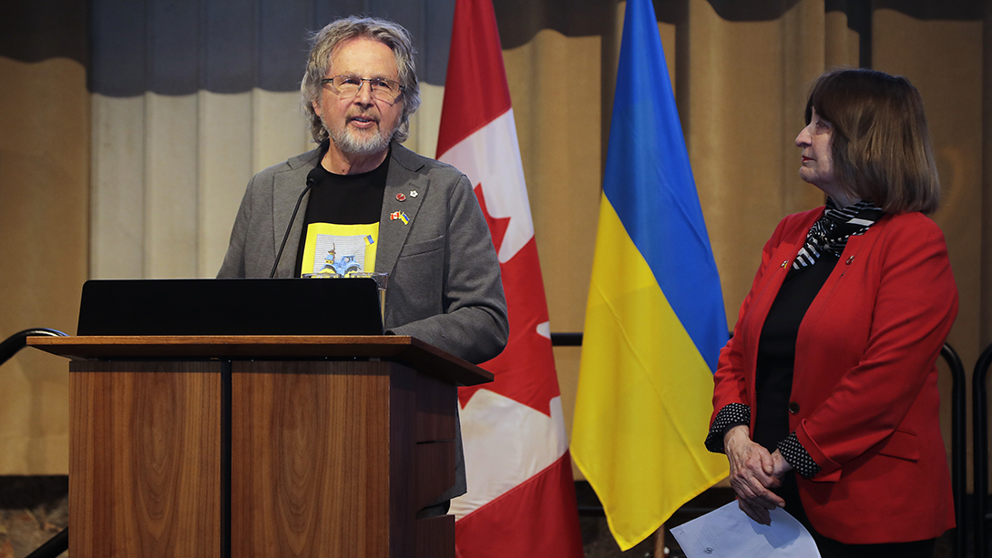 Le sénateur Stan Kutcher et la sénatrice Donna Dasko au podium, devant les drapeaux du Canada et de l’Ukraine.