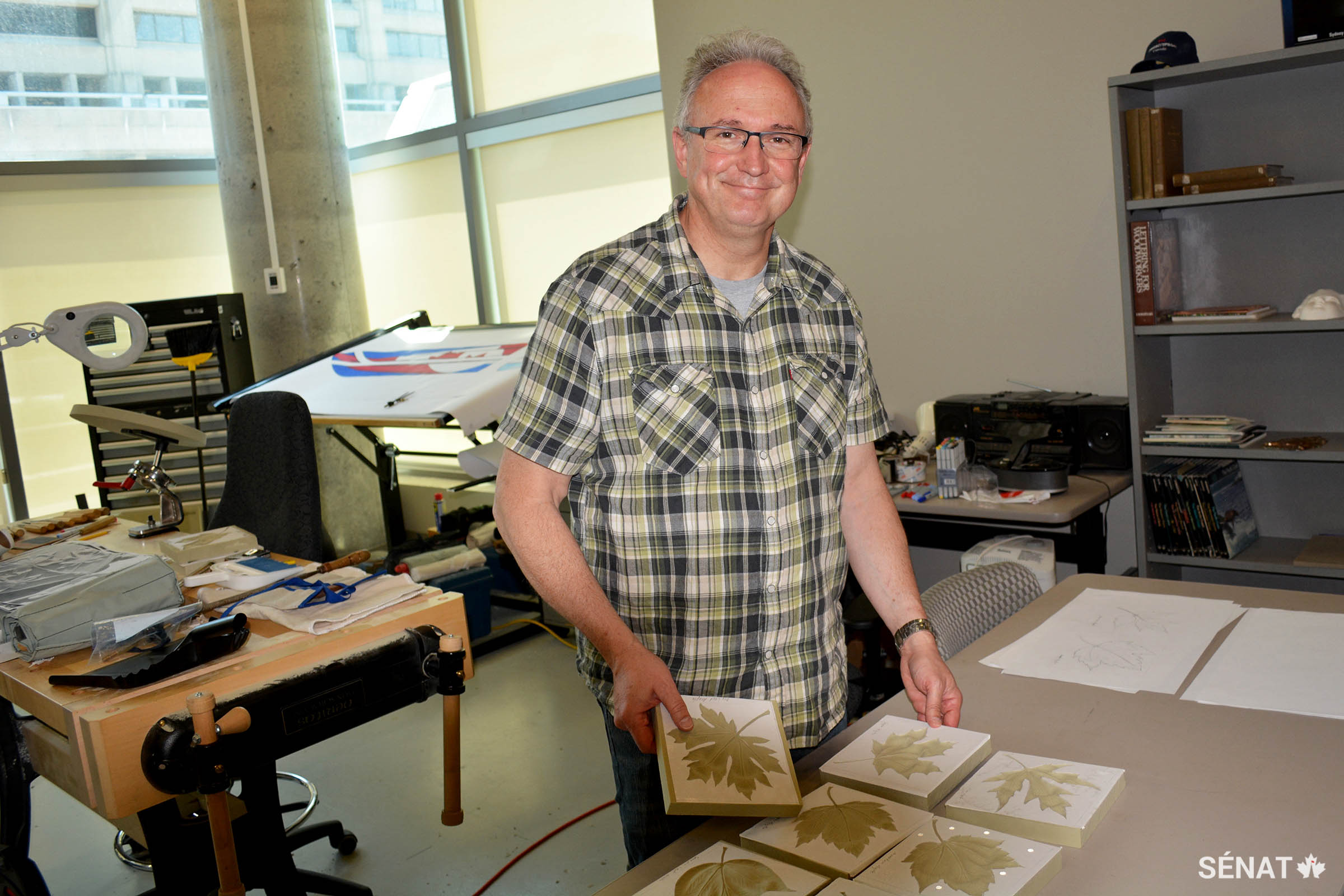Le sculpteur du Dominion, Phil White, qui a conçu la plupart des éléments décoratifs dans la nouvelle Chambre du Sénat, inspecte ses sculptures de feuilles d’érable.