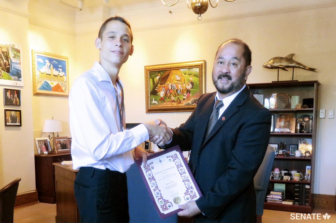 Student Andrew Arden receives a certificate of appreciation from Senator Tobias Enverga.