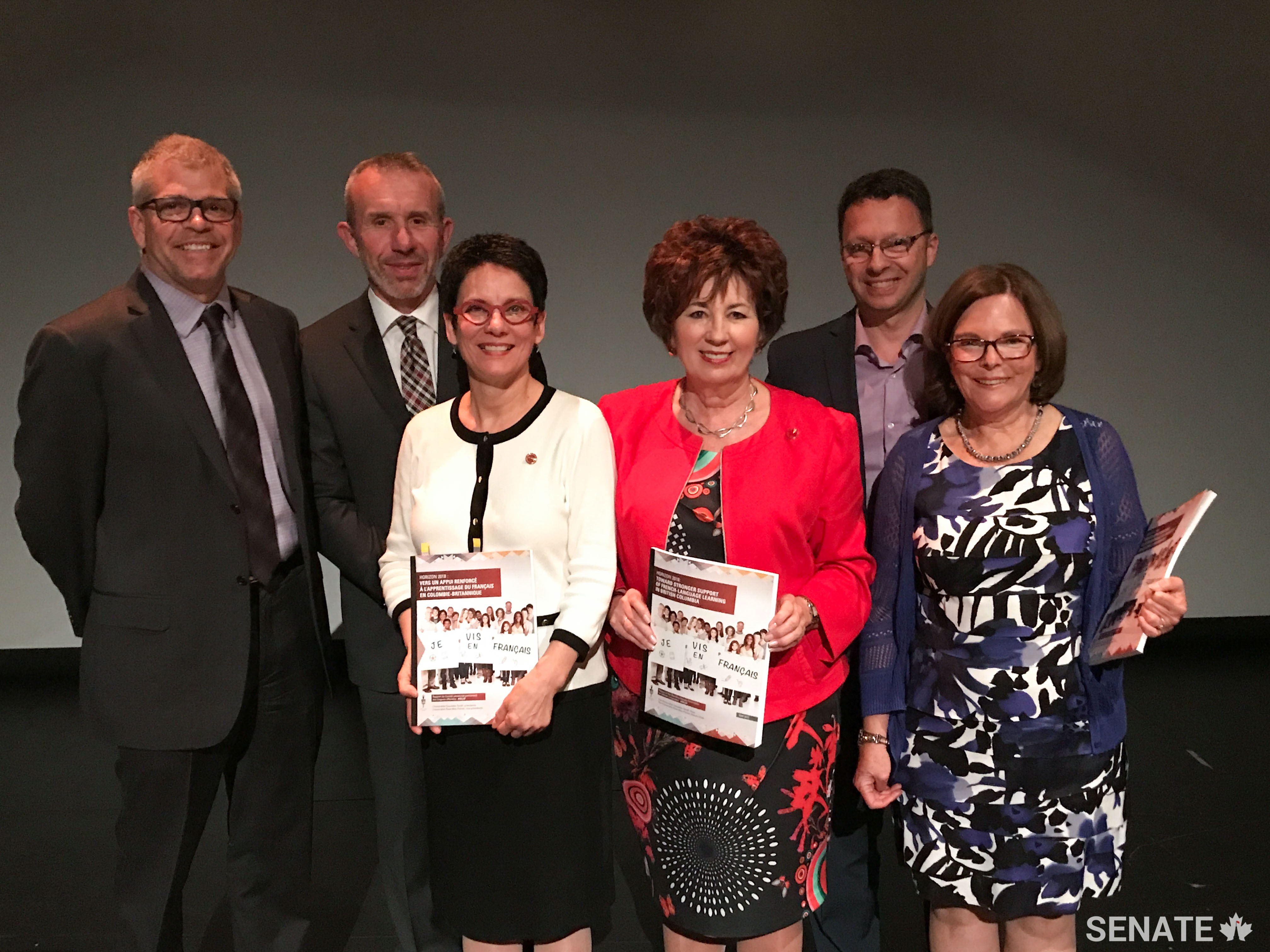 After releasing a report on the status of French-language education in British Columbia, senators Claudette Tardif (centre-right) and Raymonde Gagné (centre-left) pose for a photo with French-language advocates.