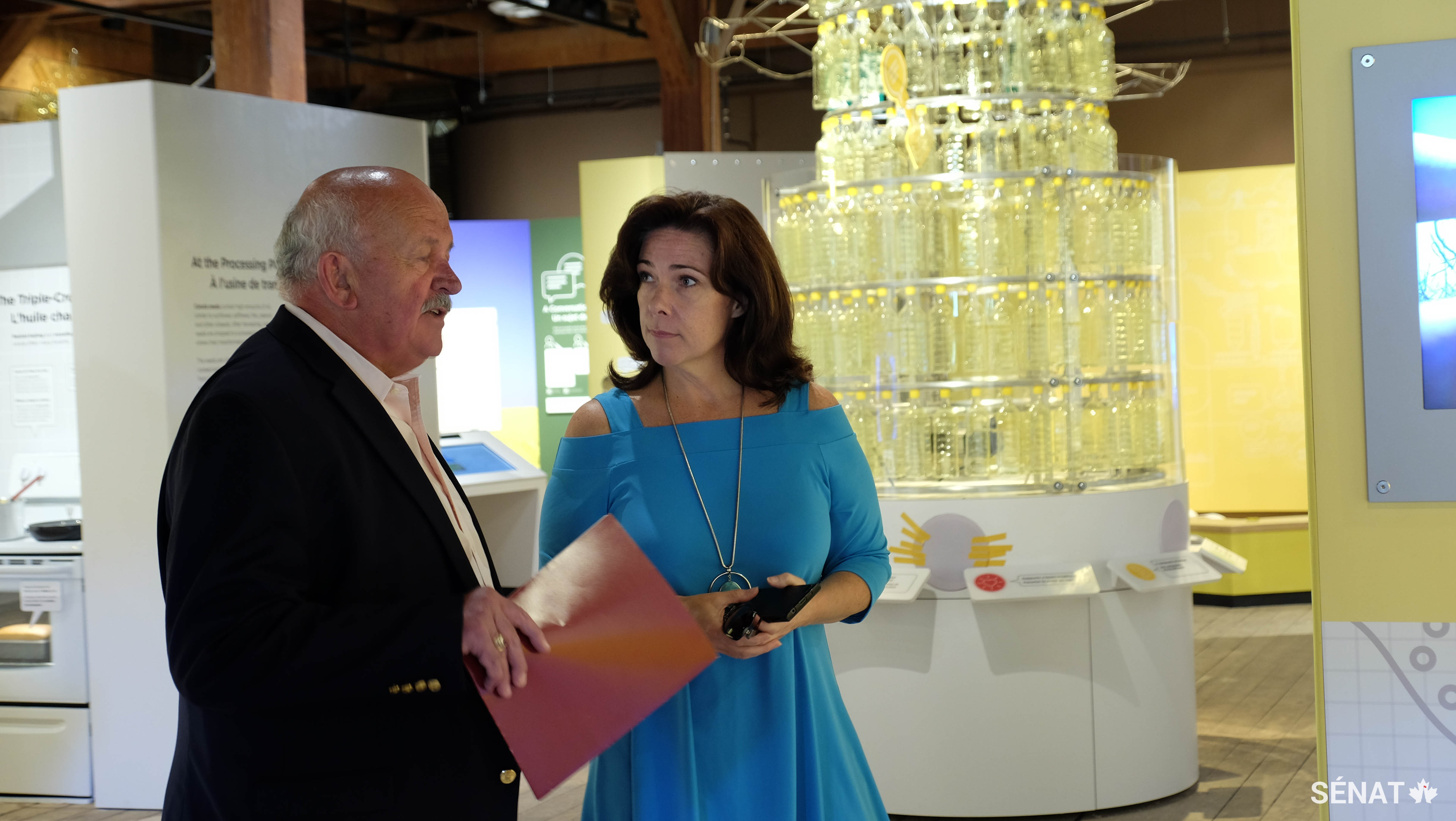 Le sénateur Terry Mercer, en compagnie de la directrice générale du Musée de l’agriculture et de l’alimentation du Canada, <a href='https://ingeniumcanada.org/ingenium/societe/equipe-de-direction.php' target='_blank'>Kerry-Leigh Burchill</a>, discute de l’une des grandes réalisations agricoles du Canada à l’exposition Canola ! Innovation en croissance, en date du vendredi 25 août 2017. Le Comité sénatorial de l’agriculture et des forêts a tracé le parcours du canola canadien, des champs aux marchés étrangers, dans son rapport de mai 2017, intitulé <a href='https://sencanada.ca/fr/sencaplus/nouvelles/les-agriculteurs-et-producteurs-daliments-du-canada-doivent-avoir-acces-au-monde-entier/' target='_self'><em>L’accès au marché mondial : donner le monde aux producteurs et transformateurs canadiens.</em></a>