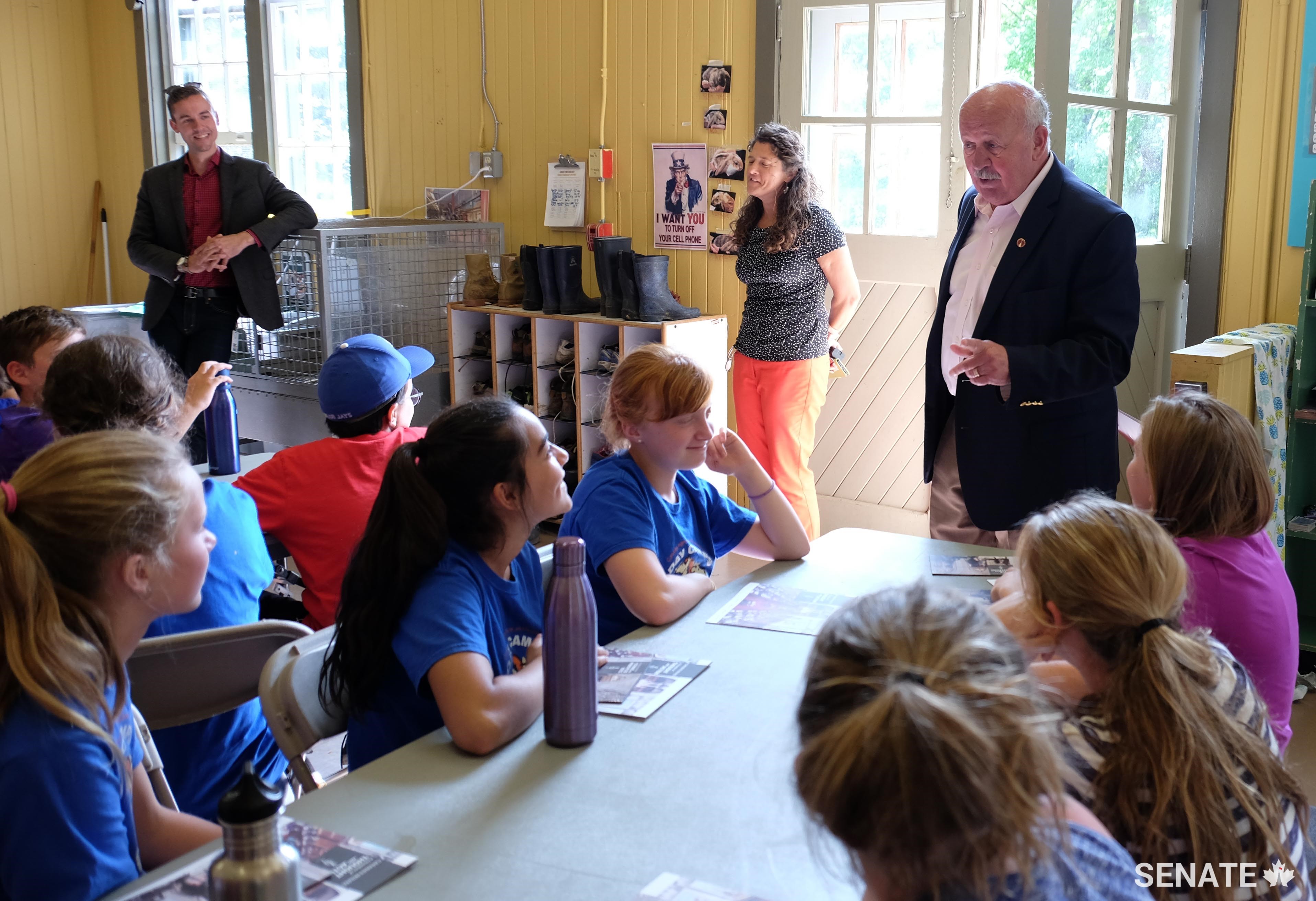 Participants in the Canada Agriculture and Food Museum’s <a href='https://ingeniumcanada.org/agriculture/whats-on/junior-farmer-camp.php' target='_blank'>Junior Farmer Camp</a> talk cows with Senator Mercer prior to attending the camp’s Calf Show — a culmination of the week’s lessons where campers show off their "adopted" calf to friends and family.