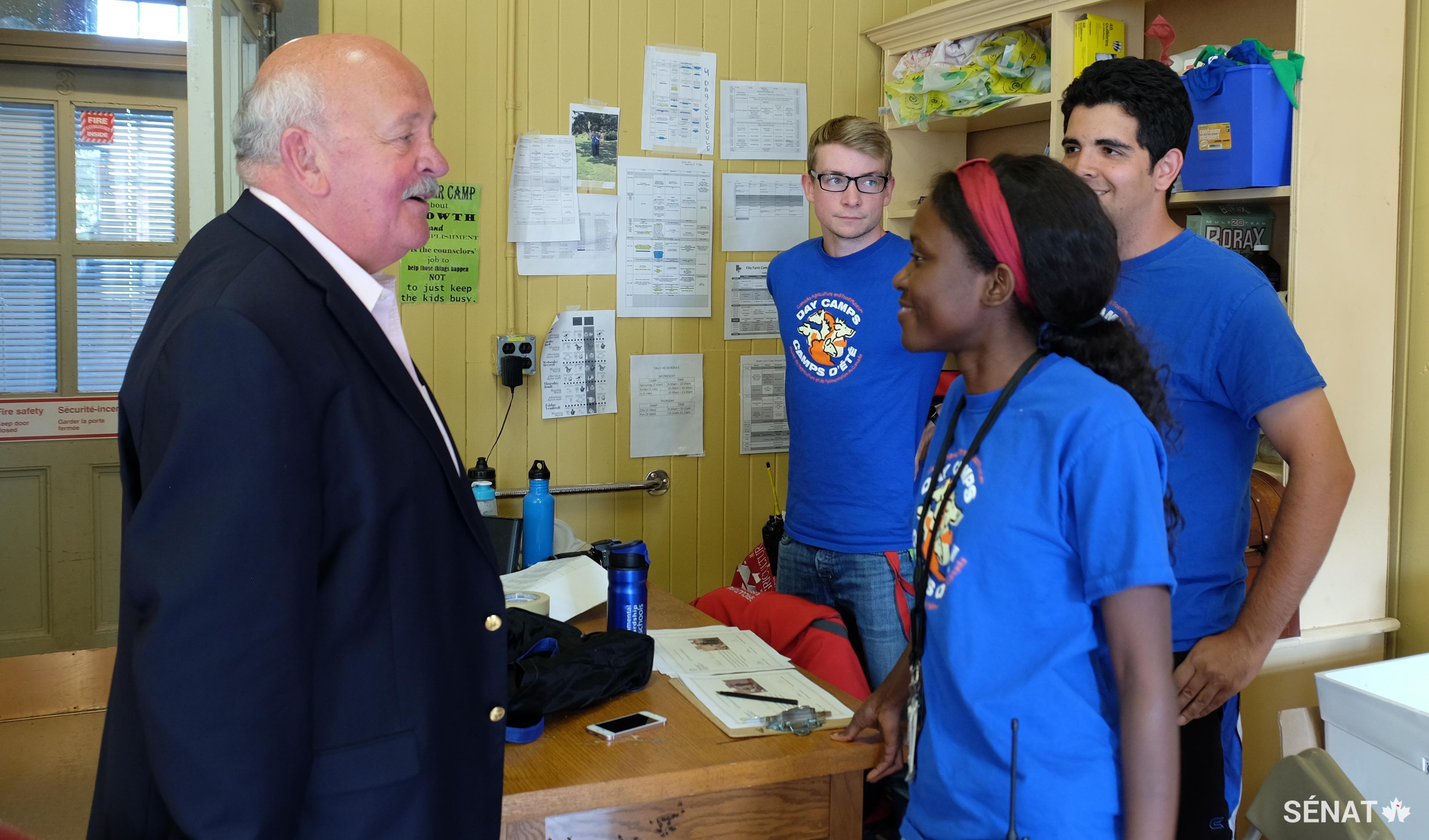 Le sénateur Mercer rencontre des employés du camp du musée (à partir de la droite) : Adam Hassen, Patricia Burhunduli et Tom Noyes Roberts. Les employés des camps d’été du musée sont souvent de futurs enseignants ou des étudiants avec une expérience agricole.