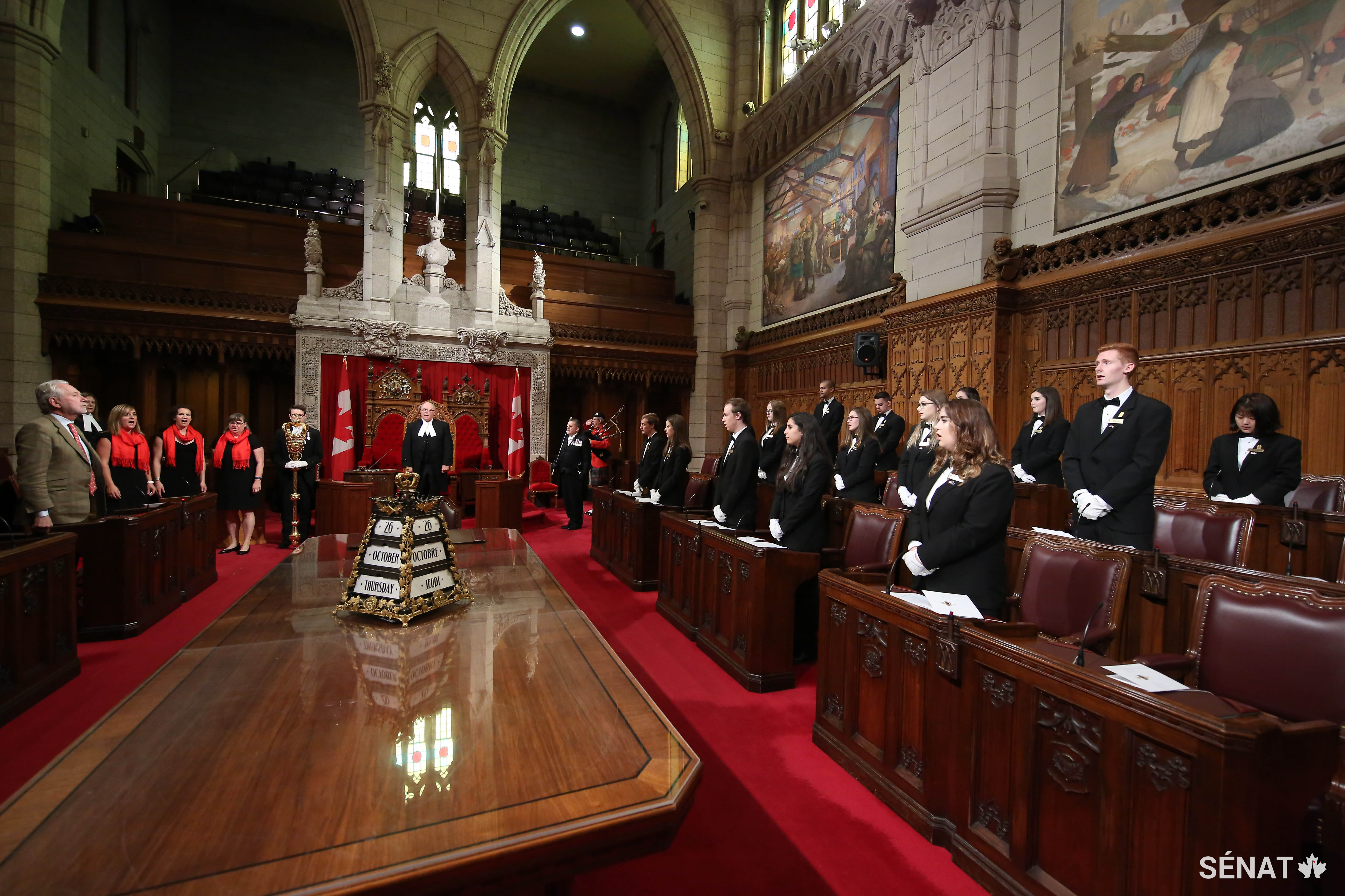 Le Président George J. Furey, accompagné du sénateur Peter Harder, représentant du gouvernement au Sénat, et les pages du Sénat se lèvent pour chanter l’hymne national avant de prêter serment à la reine et à leur pays.
