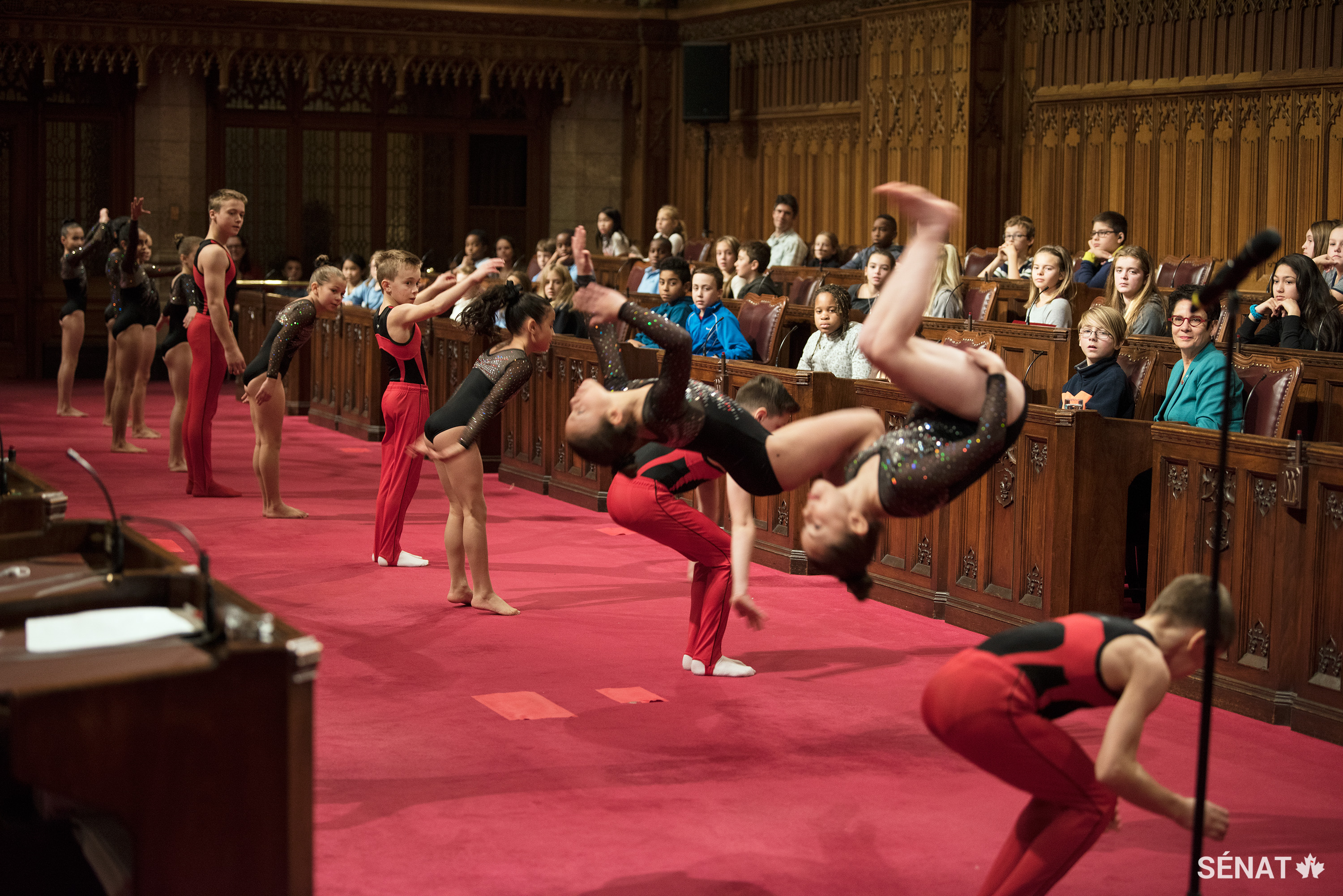 Des membres d’UniGym Gatineau font des saltos arrière pendant la Journée nationale de l’enfant dans la Chambre du Sénat.