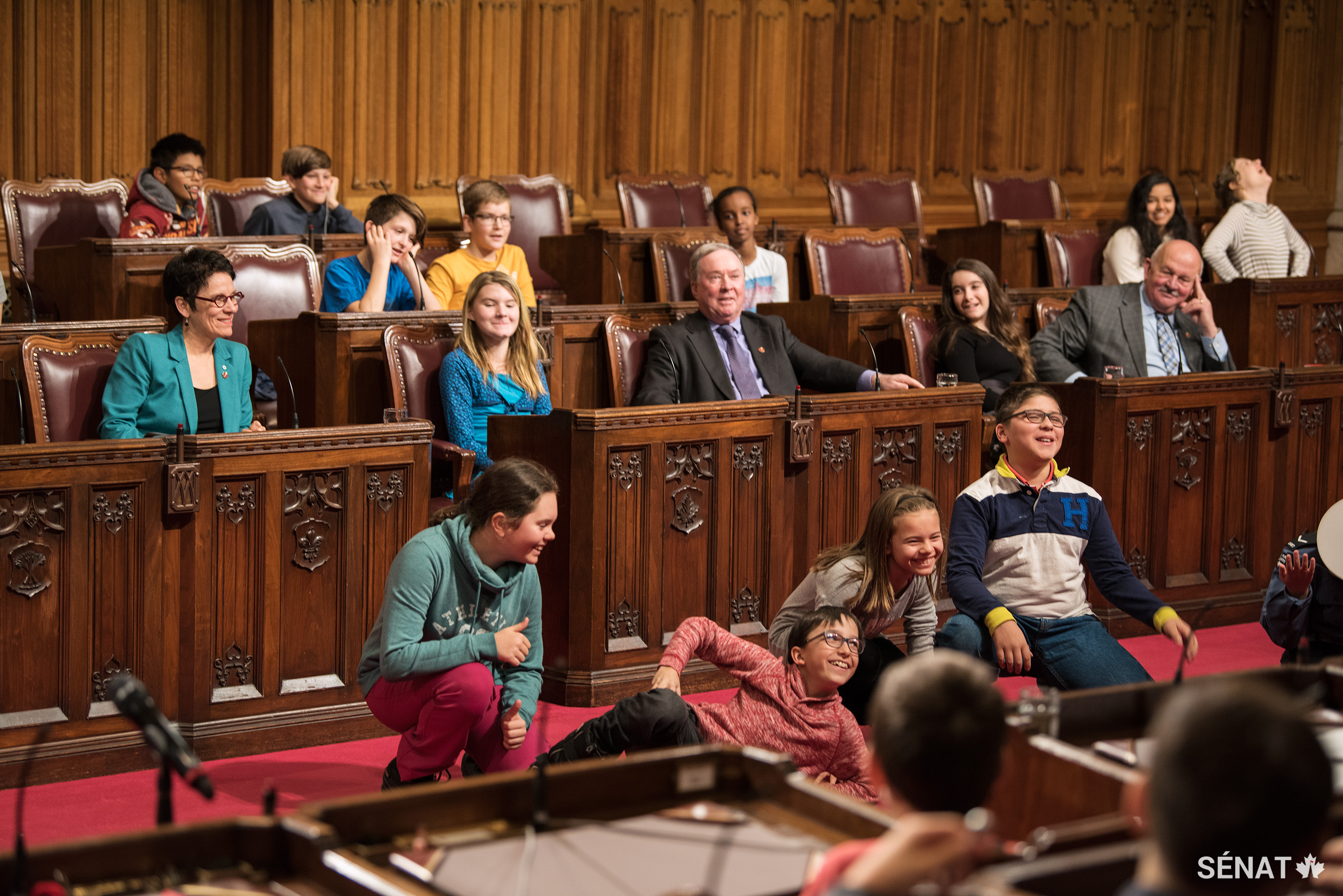 Des volontaires désignés interprètent des scènes sur le parquet de la Chambre rouge pendant un jeu d’improvisation mené par des membres d’Improv Embassy.