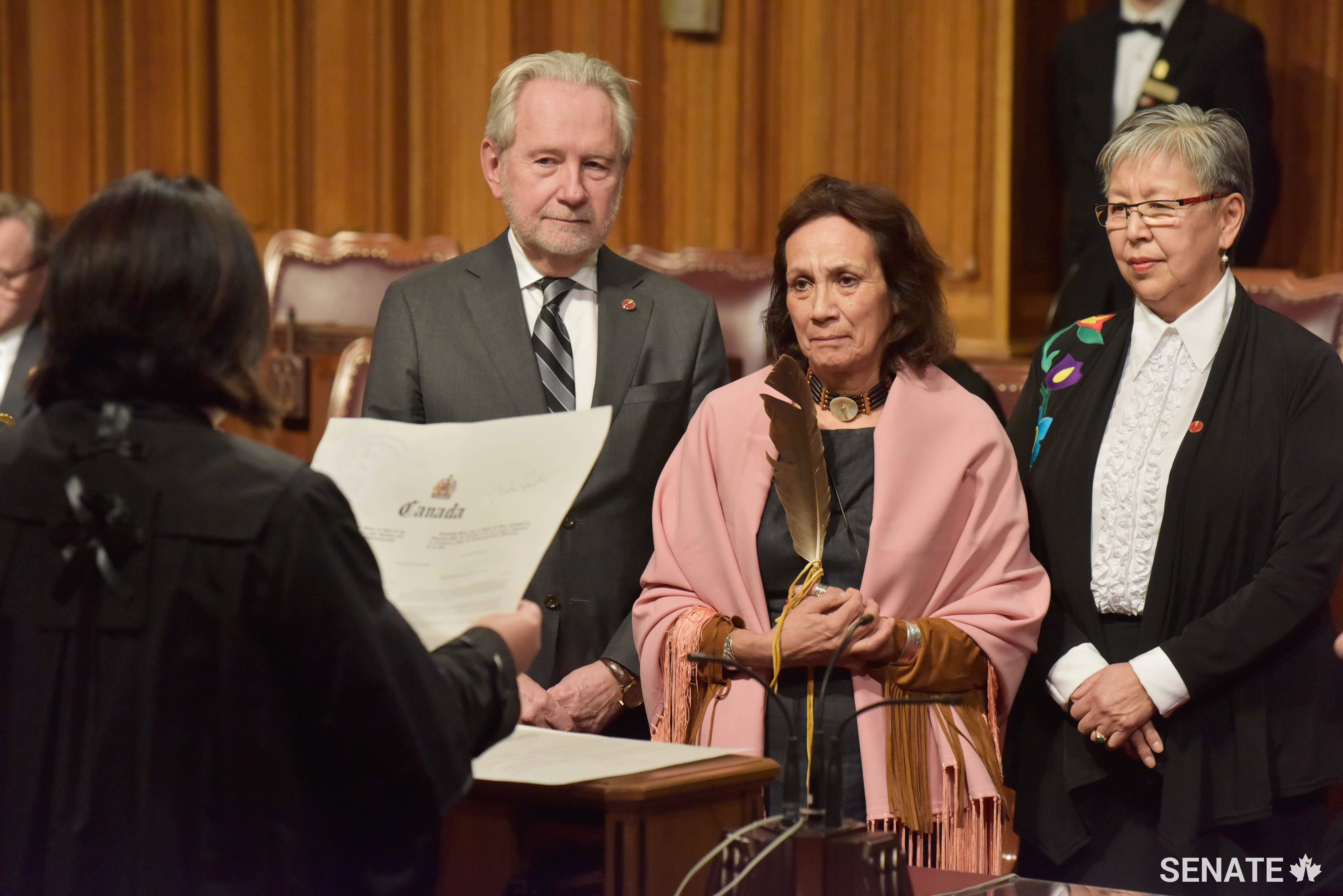 Senator Mary Jane McCallum (centre), joined by Senator Peter Harder (left) and Senator Lillian Eva Dyck (right), is sworn into the Senate. 