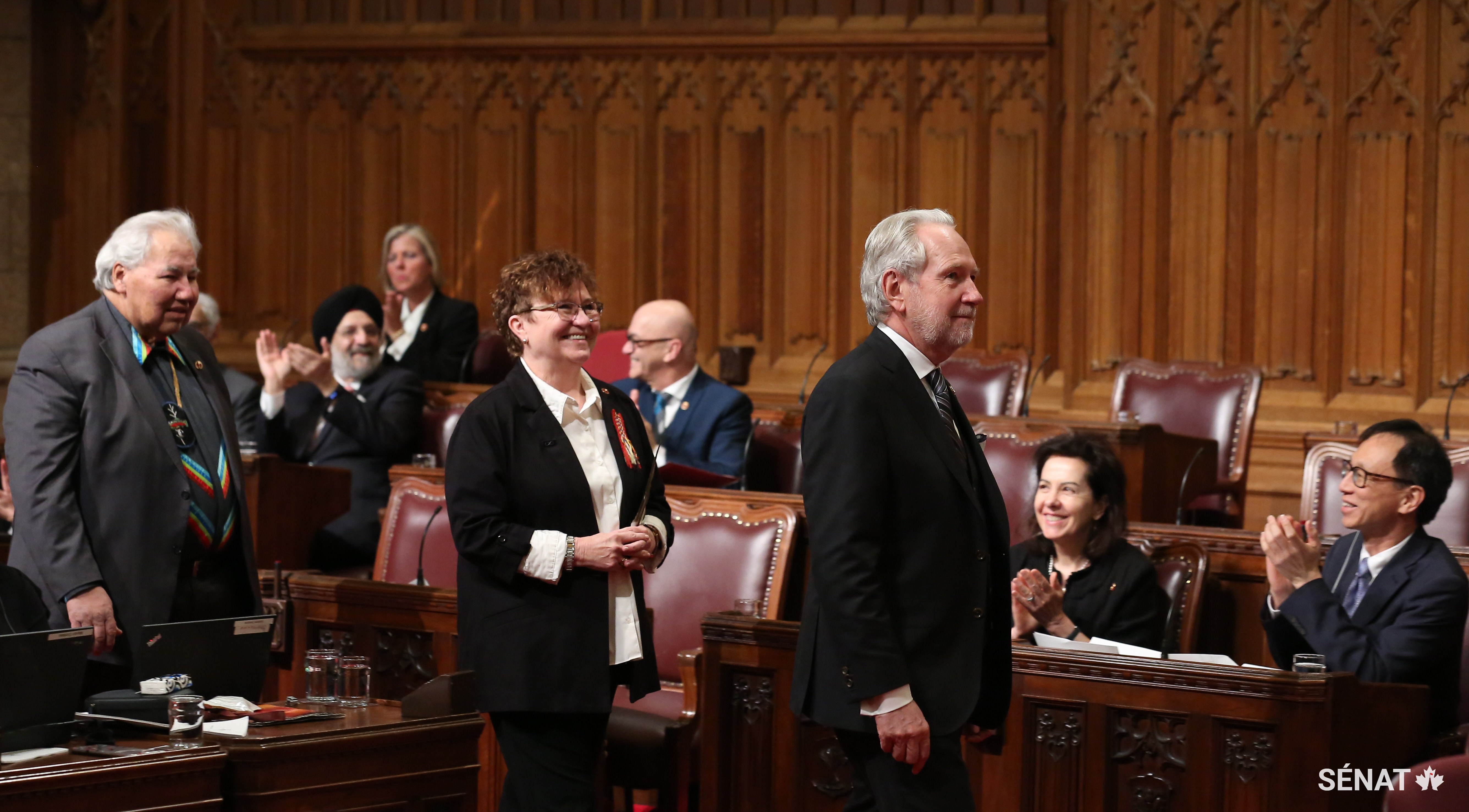 La sénatrice Yvonne Boyer (au centre), accompagnée du sénateur Peter Harder (à droite) et du sénateur Murray Sinclair (à gauche), est accueillie dans la Chambre du Sénat.