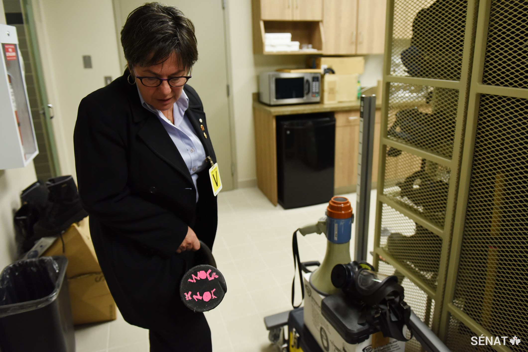 La sénatrice Kim Pate examine un bélier dans le dépôt d’armes de la prison. À son extrémité, on a écrit les mots « knock knock » avec du ruban adhésif rose.