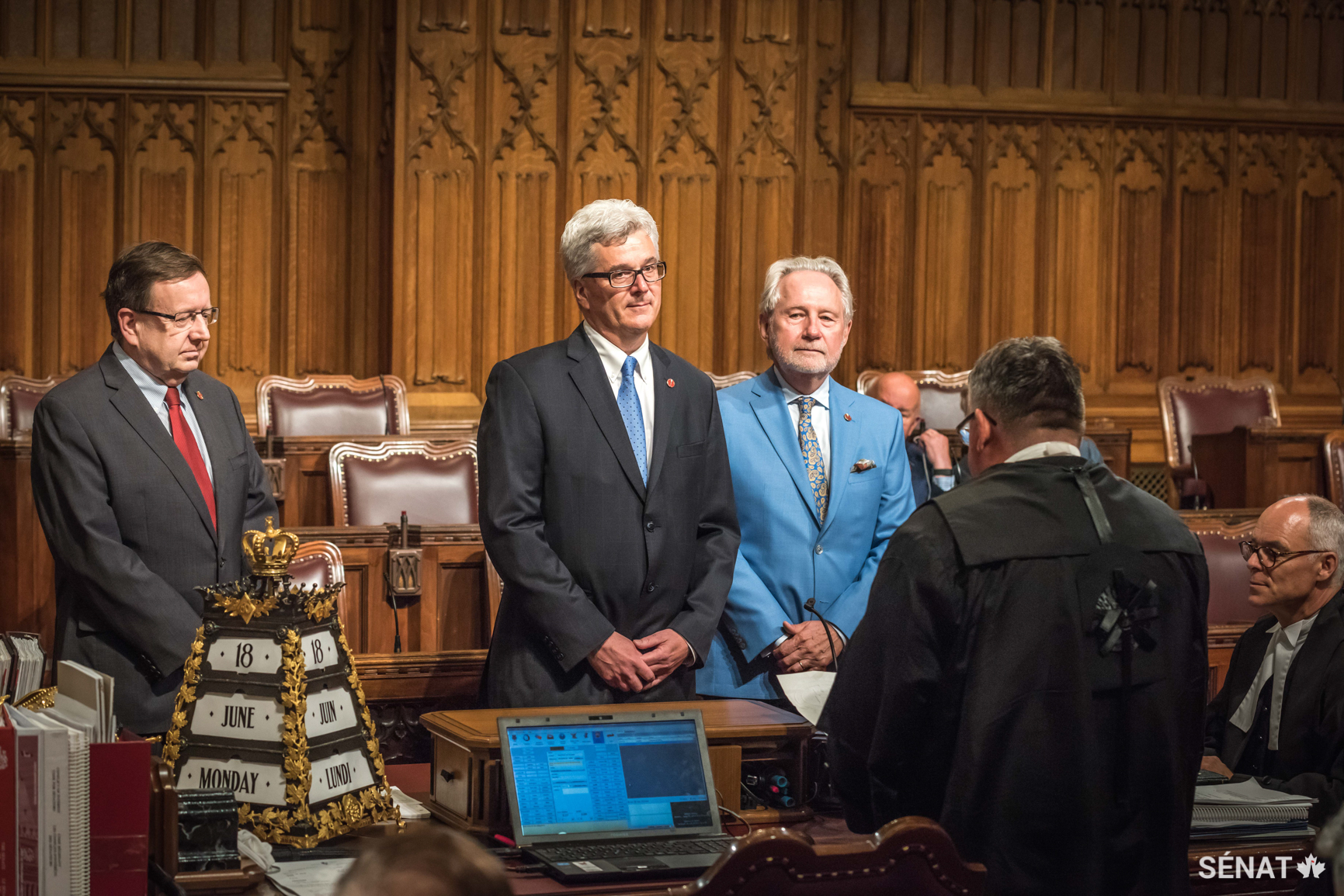 Le sénateur Colin Deacon, au centre, est assermenté dans la Chambre du Sénat le vendredi 15 juin 2018, alors que les sénateurs Peter Harder et Percy Downe observent.