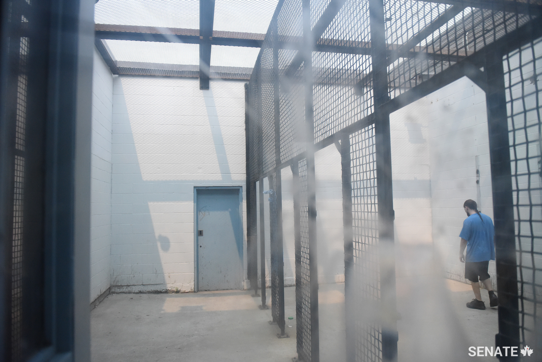 A prisoner paces in an outdoor recreation yard.