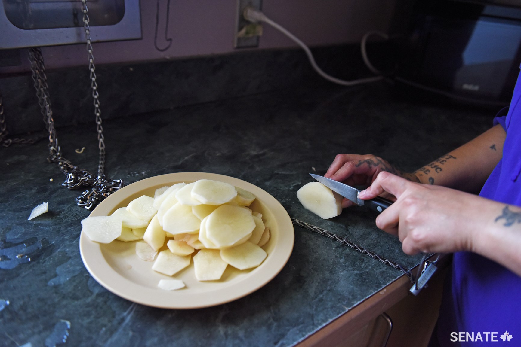 A woman in a medium-security Pathways house — a program for Indigenous prisoners —prepares fried potatoes with a chained-up knife. She was cooking to share with the 10 other women in her unit. To be eligible to live in this unit, Correctional Service Canada requires women to demonstrate readiness and commitment to rehabilitation; the next step from this unit is usually for the person to be reclassified and transferred to minimum security or released.