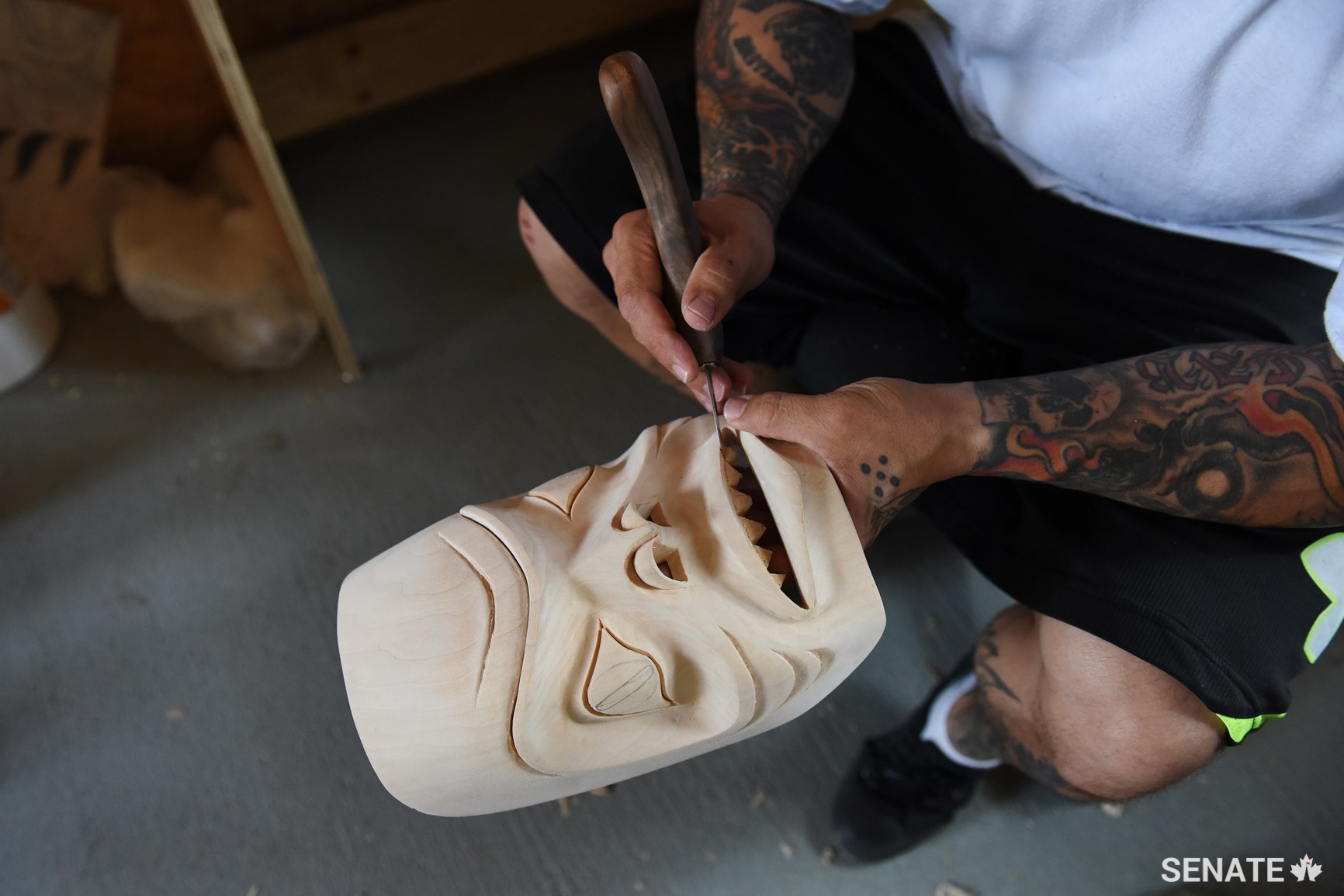 A prisoner carves a traditional cedar mask in a workshop.