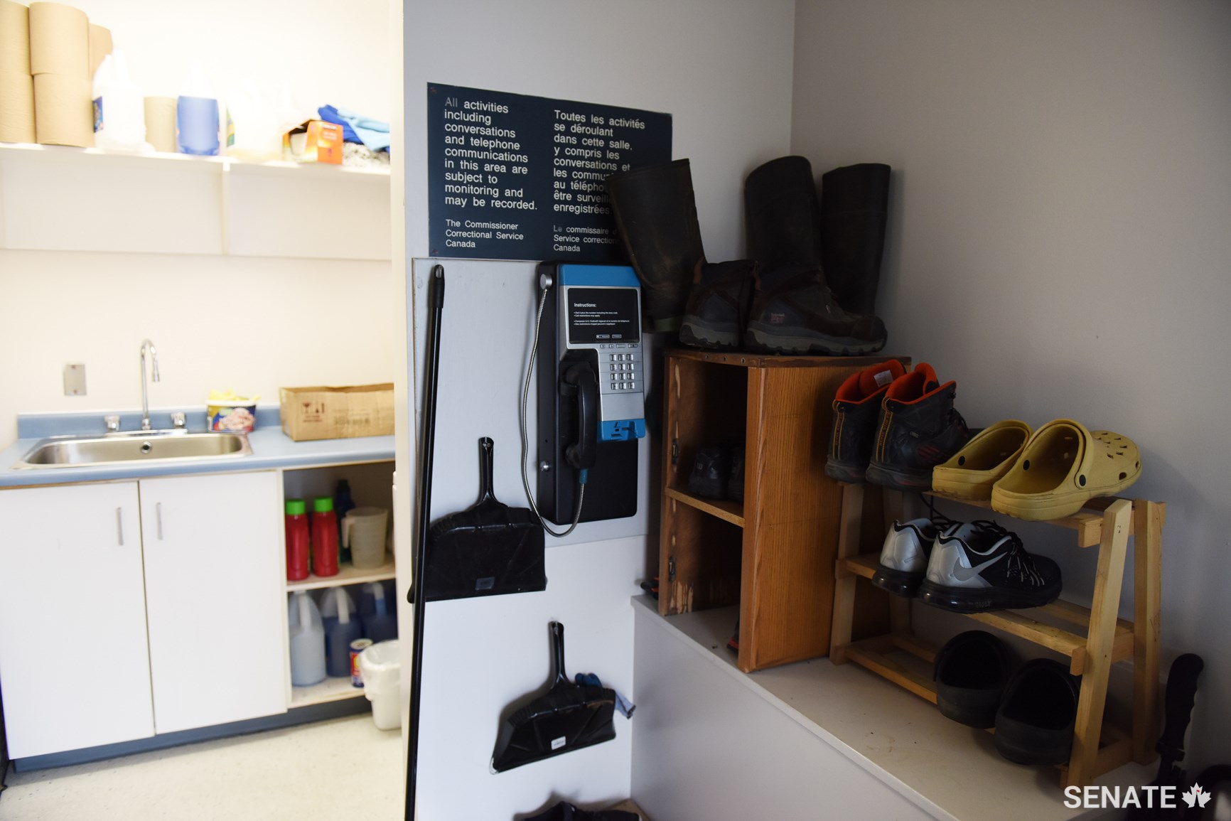 A payphone and shoes at the entrance area of a minimum-security living unit that is shared by six men.