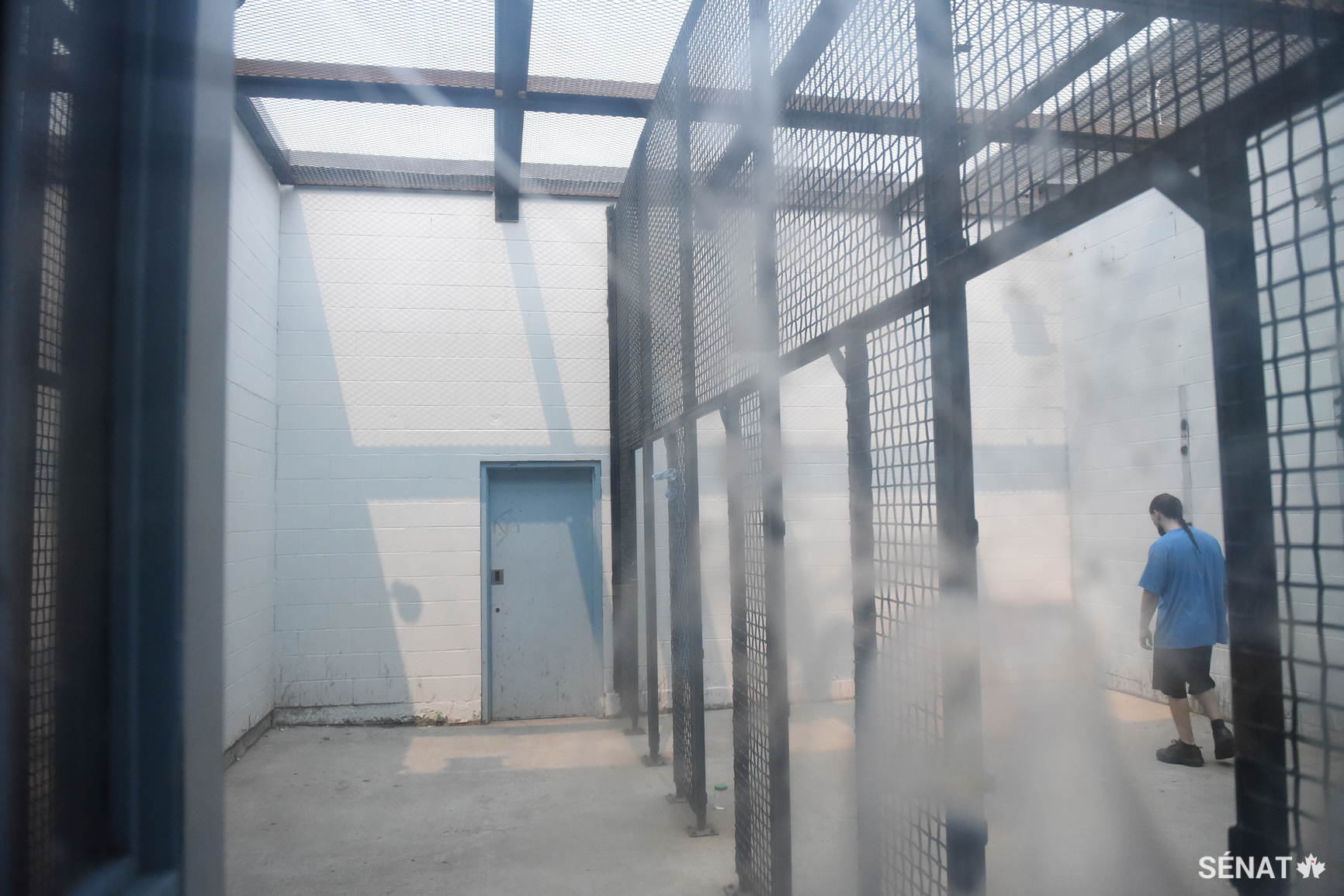 Un prisonnier fait les cent pas dans une cour de récréation extérieure.