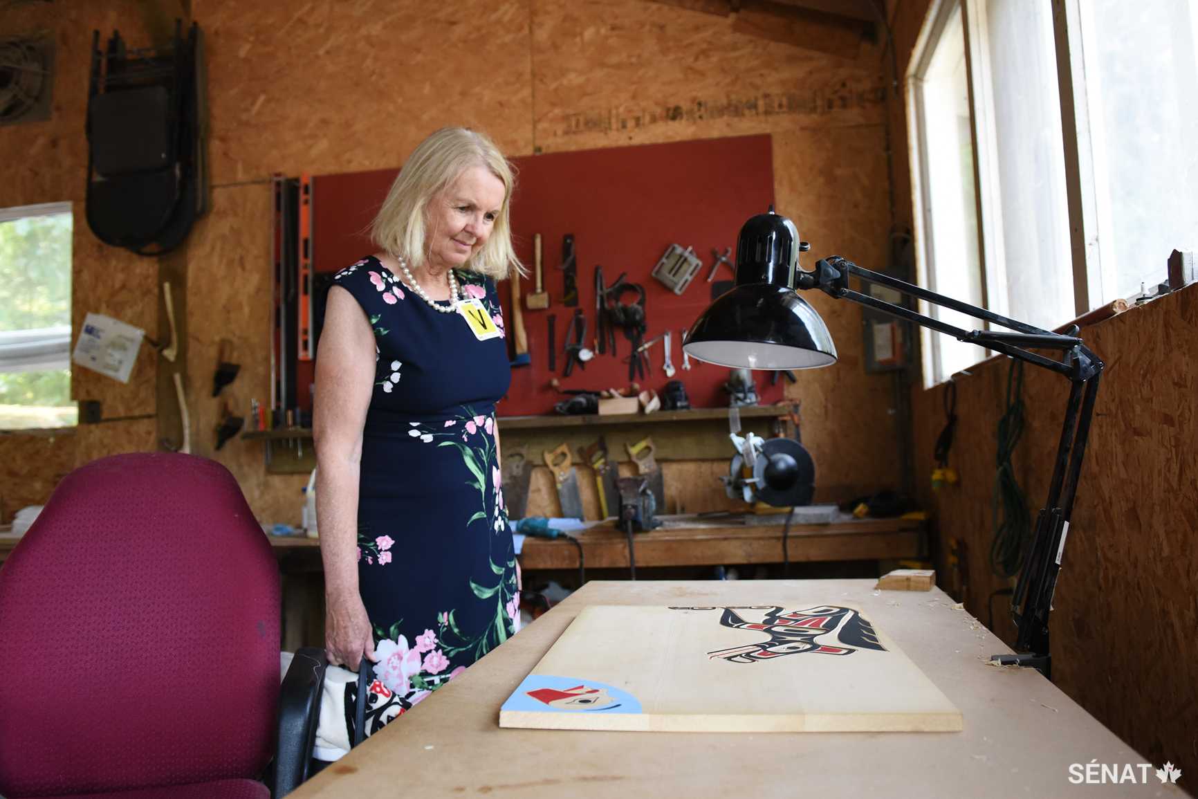La sénatrice Cordy admire une peinture en préparation dans un atelier.