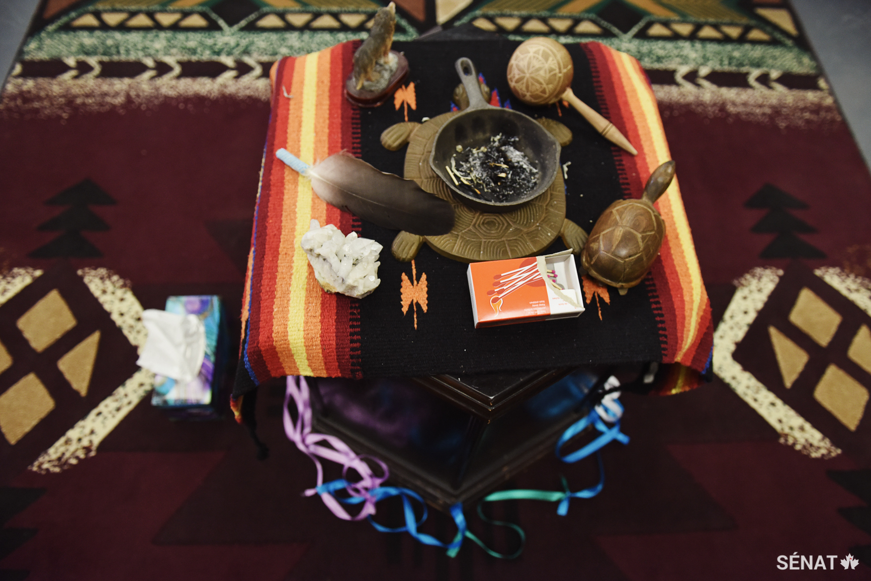 Des objets cérémoniels reposent sur une table dans une salle du <em>Stan Daniels Healing Centre</em>, qui procure un soutien aux hommes autochtones reconnus coupables d’un crime. Des programmes tels qu’« <em>In Search of your Warrior</em> » (« À la recherche de ton guerrier ») mettent l’accent sur la prévention de la violence; les leçons sont communiquées grâce à des cérémonies et des enseignements donnés par des anciens. L’objectif consiste à aider les hommes autochtones à assumer la responsabilité de leurs actions et à comprendre comment les mauvais traitements, les traumatismes intergénérationnels, le chagrin et les pertes qu’ils ont subies ont influé sur leur comportement.