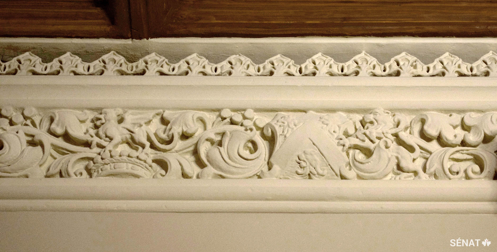 Les éléments des armoiries de lord Monck sont disposés, de façon non conventionnelle, côte à côte le long de l’étroite corniche. On y trouve notamment une couronne de vicomte doté d’un cimier en forme de dragon et un écu orné de trois têtes de lion.