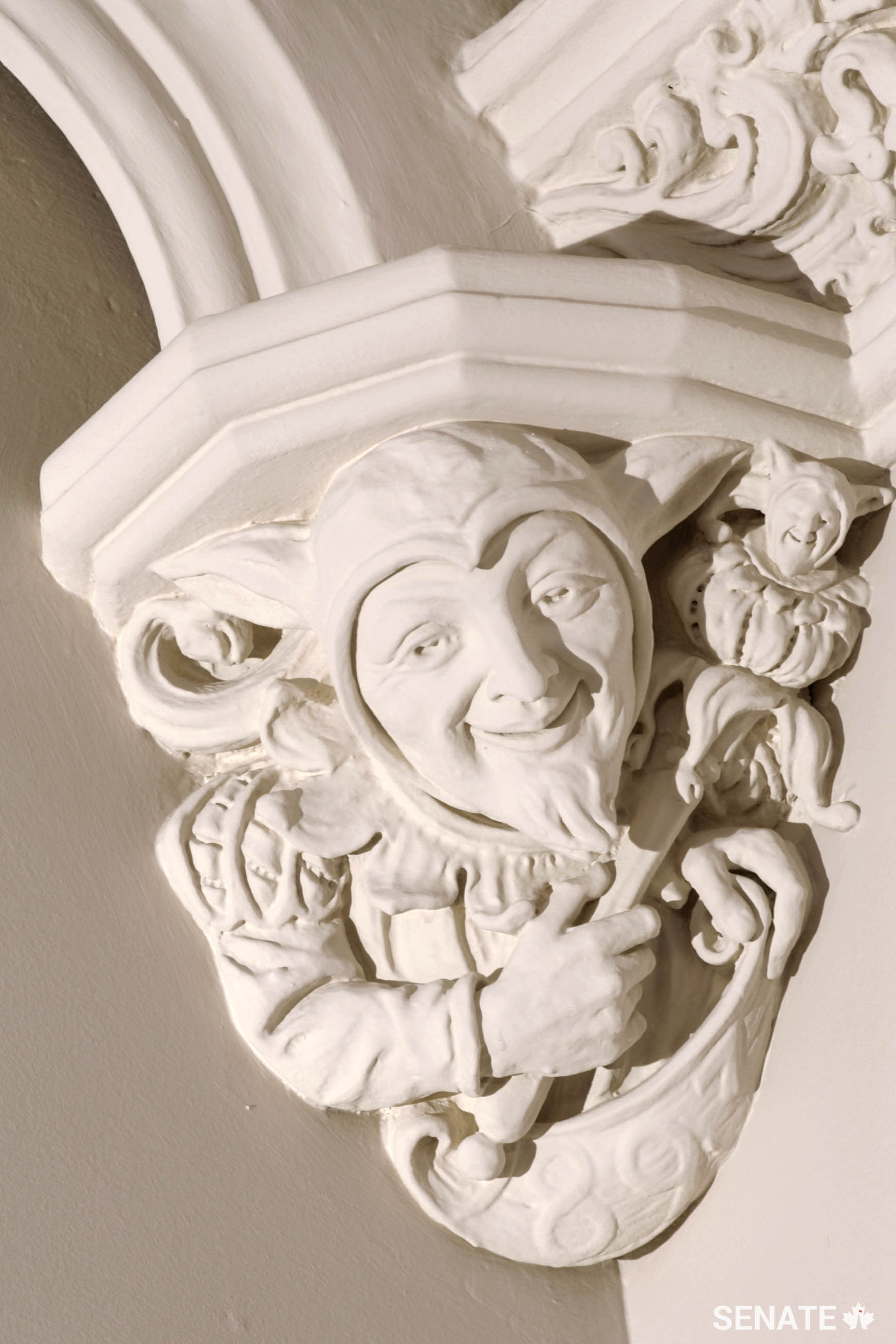 Courtly figures, including this smirking jester, bookend the 12 coats of arms.