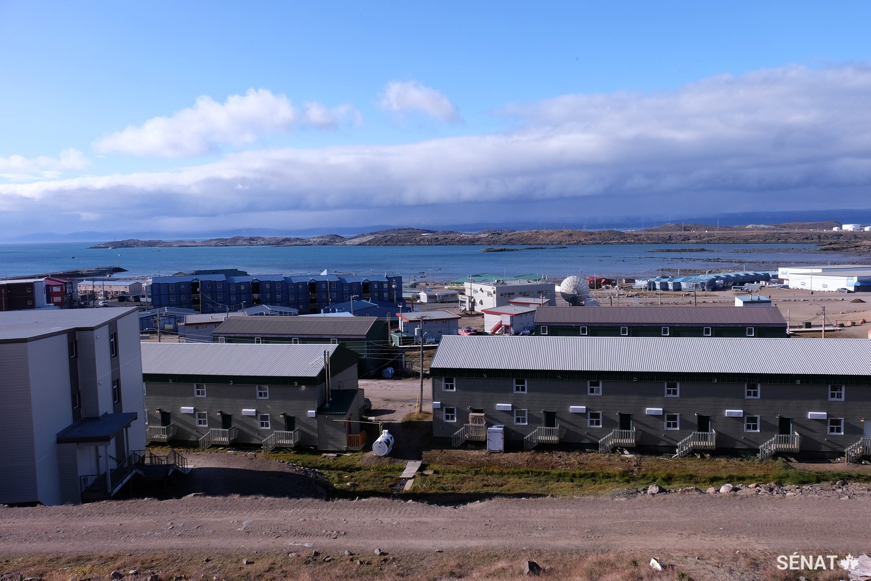 Des maisons aux abords du passage Koojesse, à Iqaluit, au Nunavut. Seulement 62 % des communautés du territoire ont des logements adéquats. Les frais de construction des maisons ou de l’infrastructure dans le Nord peuvent être 150 % plus élevés qu’au Sud, étant donné entre autres la courte durée de la saison de construction (et de transport des matériaux) et les difficultés que posent le climat.