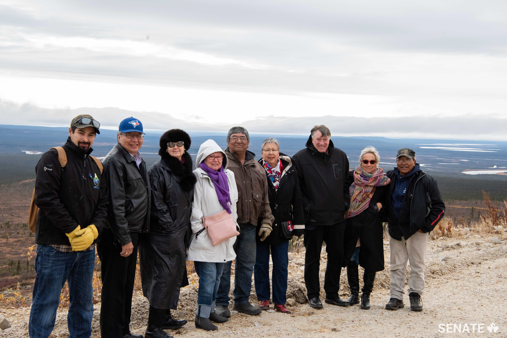 Senators join Old Crow community leaders on a tour to the top of a mountain. During the tour of the community, committee members saw impressive infrastructure including a large solar power project and a centre where researchers are studying permafrost.