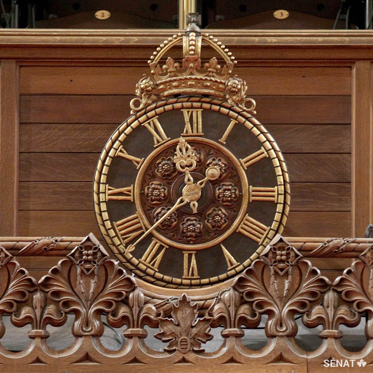 Différents symboles héraldiques des Français et des Anglais, comme la fleur de lys, la rose Tudor et la couronne Tudor, enjolivent une horloge devant la tribune publique de la Chambre du Sénat.