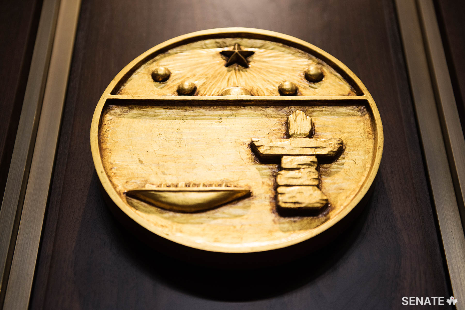 The shield of Nunavut depicts the midnight sun and the North Star above a qulliq, a traditional Inuit oil lamp, and an inuksuk, a stone navigational marker.