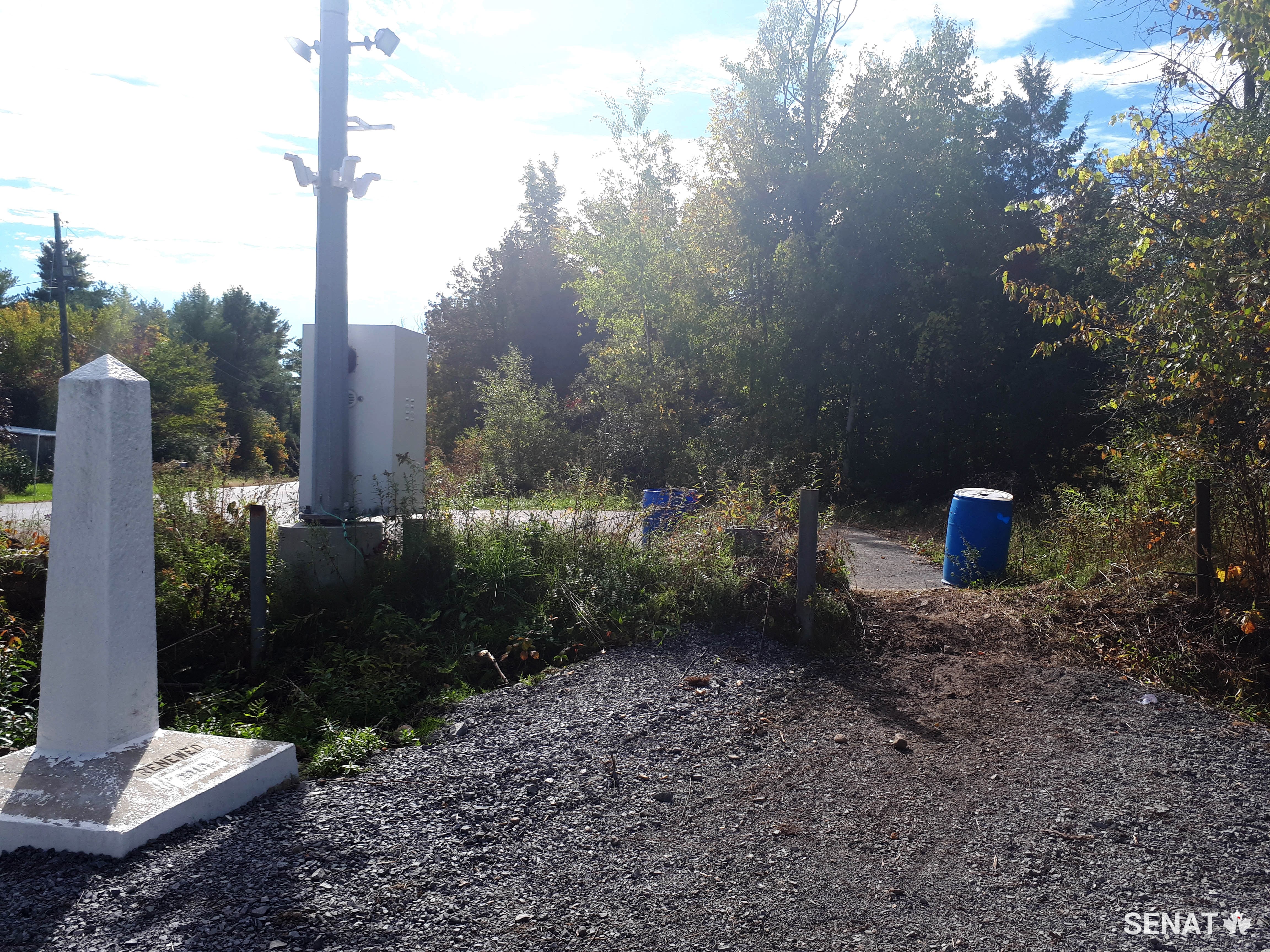 Des panneaux signalent la frontière entre le Canada et les États-Unis à Roxham Road, au Québec. La communauté a rempli le fossé de gravier pour aider les demandeurs d'asile à franchir la frontière. (Crédit : Bureau du Sénateur André Pratte)