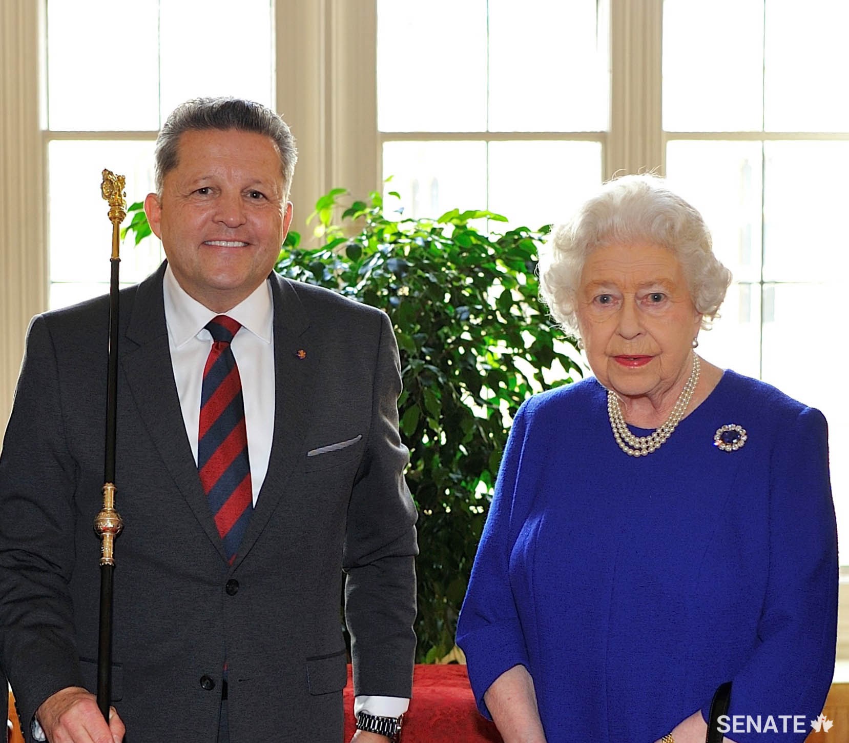 The Usher of the Black Rod, J. Greg Peters, receives the restored Black Rod from Her Majesty Queen Elizabeth II.