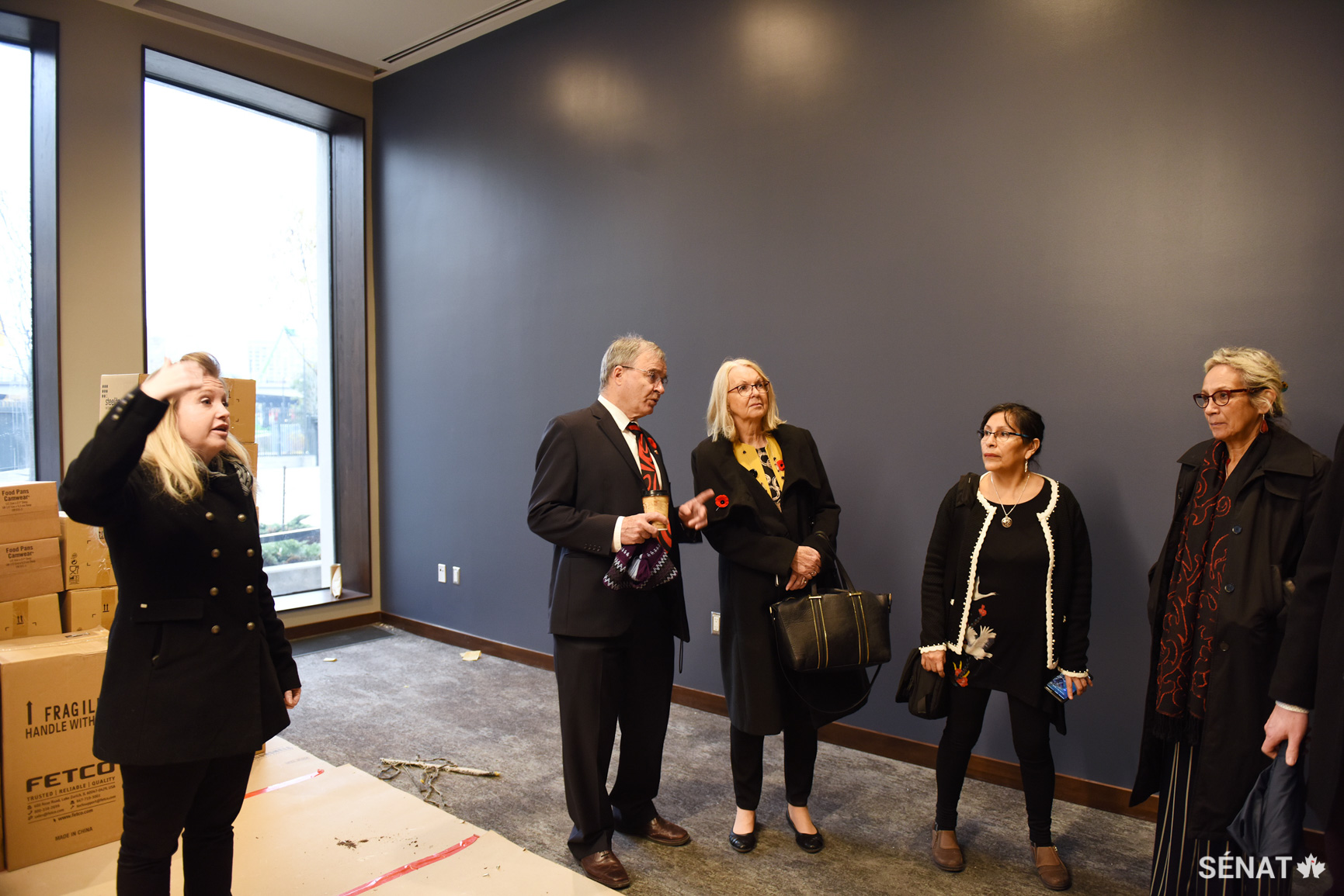 La gestionnaire de projet de Services publics et Approvisionnement Canada, Misty Campbell, à gauche, explique certaines caractéristiques d’efficacité énergétique de la nouvelle salle de lecture du Sénat au sénateur Patterson, et aux sénatrices Cordy, Galvez et McCallum. Les constructeurs ont utilisé des fenêtres avec un indice de rétention de chaleur élevé ainsi que du noyer provenant de sources durables perforé de minuscules trous pour absorber le bruit.