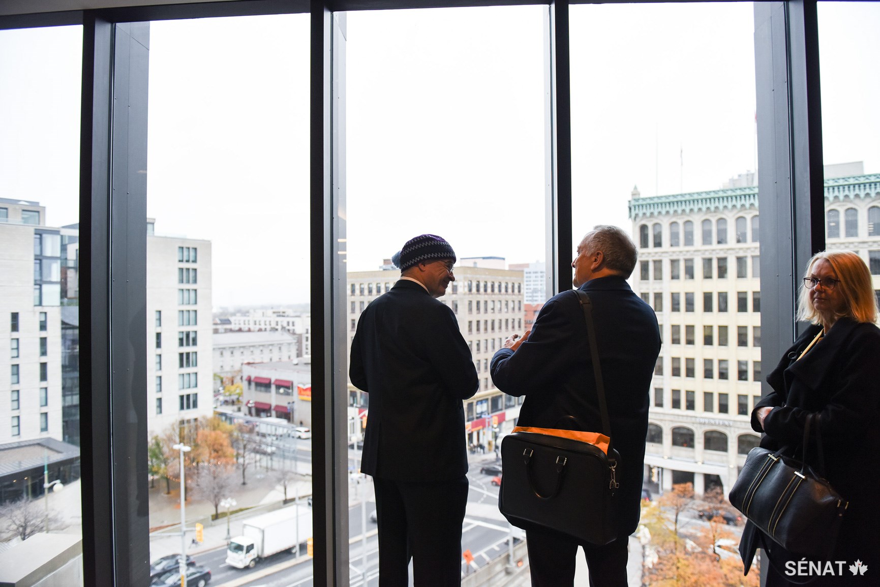 Les sénateurs Patterson et Massicotte admirent la vue à l’intersection de la rue Rideau et de la promenade Sussex à travers les fenêtres conçues pour couper les courants d’air et conserver l’air traité, optimisant ainsi le système de chauffage et de refroidissement de l’édifice du Sénat du Canada.