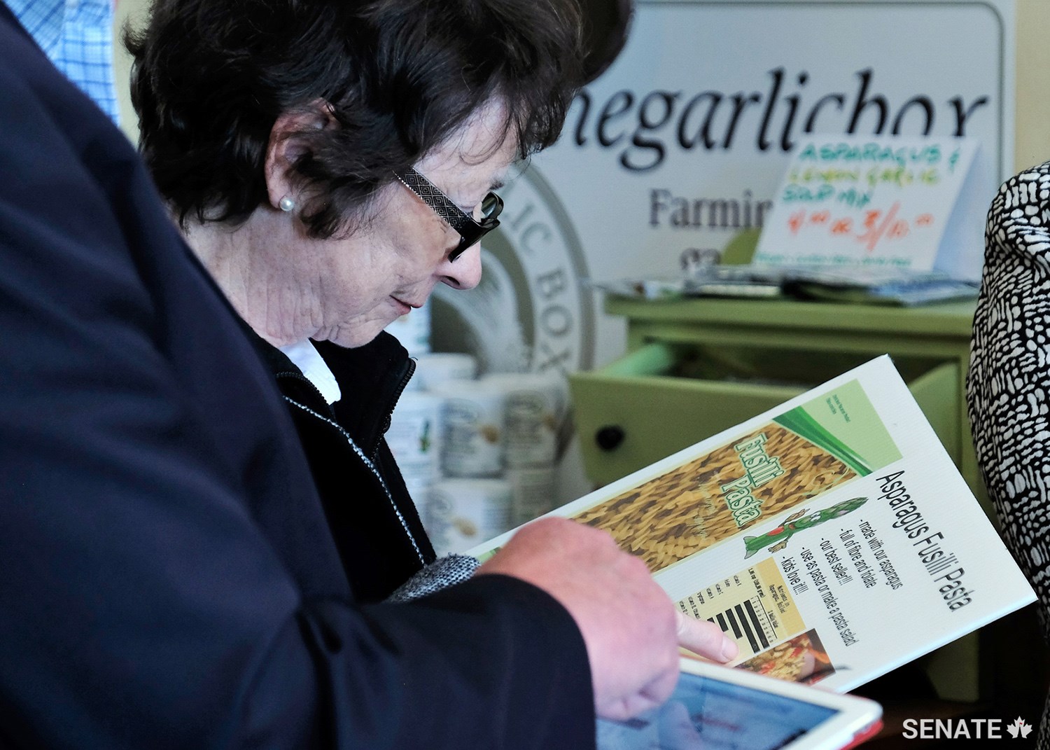 Senator Diane Griffin reads about the health benefits of asparagus pasta, an innovative, value-added food offered by a small family business in Cambridge, Ont.