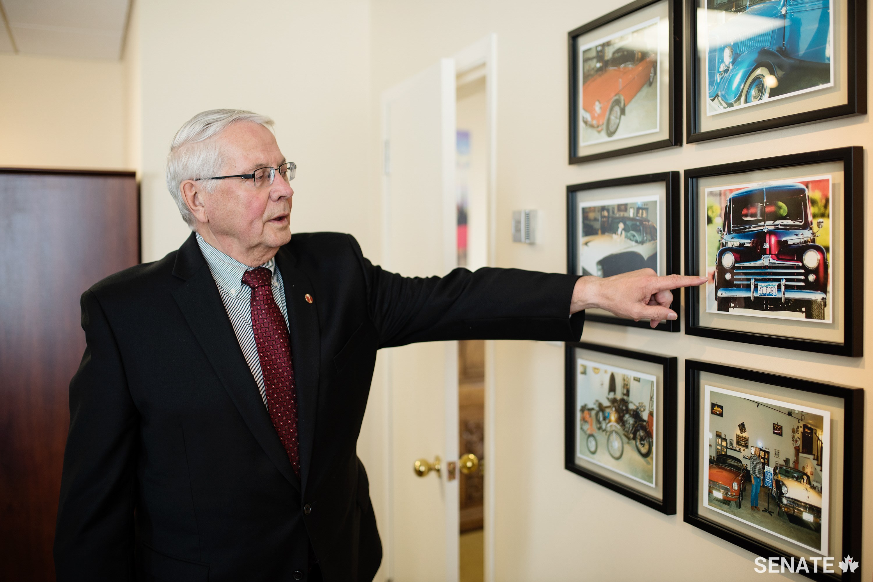 Senator Richard Neufeld points to a photo of a 1947 Ford Coupe that sits in his garage. Photos of his vintage cars hang in his Senate office.