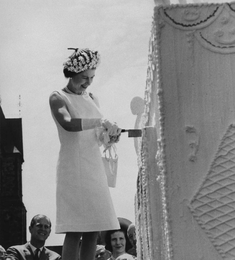 La reine Elizabeth II coupe un gâteau d’anniversaire géant de quatre étages lors des célébrations du centenaire sur la Colline du Parlement, le 1er juillet 1967. (Bibliothèque et Archives Canada)
