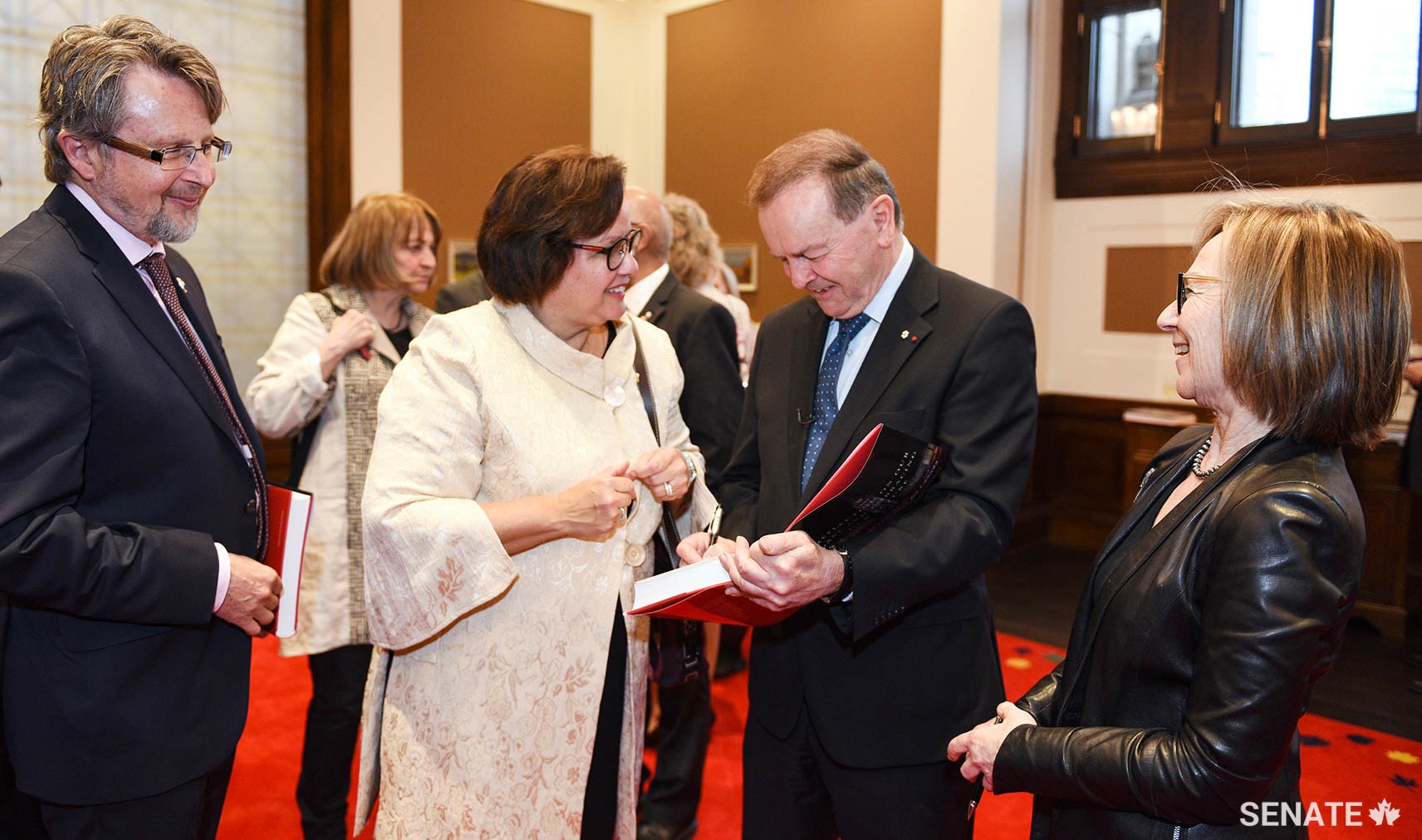 Senators Stan Kutcher and Rosemary Moodie look on as Senator Serge Joyal and Judith G. Seidman co-sign their copies of <em>Reflecting on our Past and Embracing our Future: A Senate Initiative for Canada</em> (Left to right: Senators Kutcher, Moodie, Joyal and Seidman).