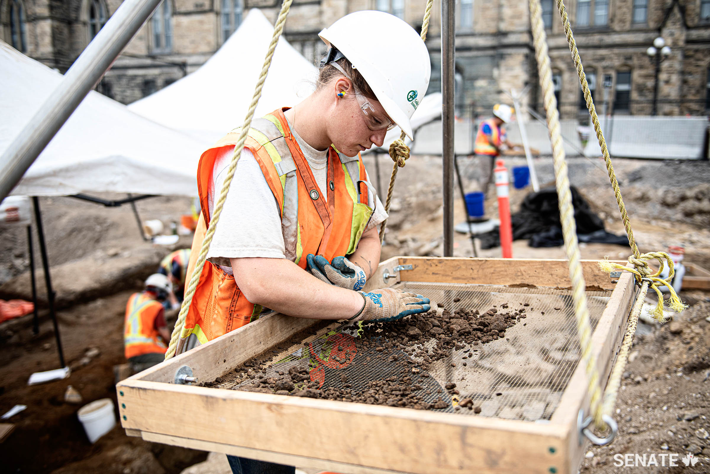 An archaeologist uses a sieve to skim soil for potential archaeological finds on the site of a military guardhouse unearthed on Parliament Hill.