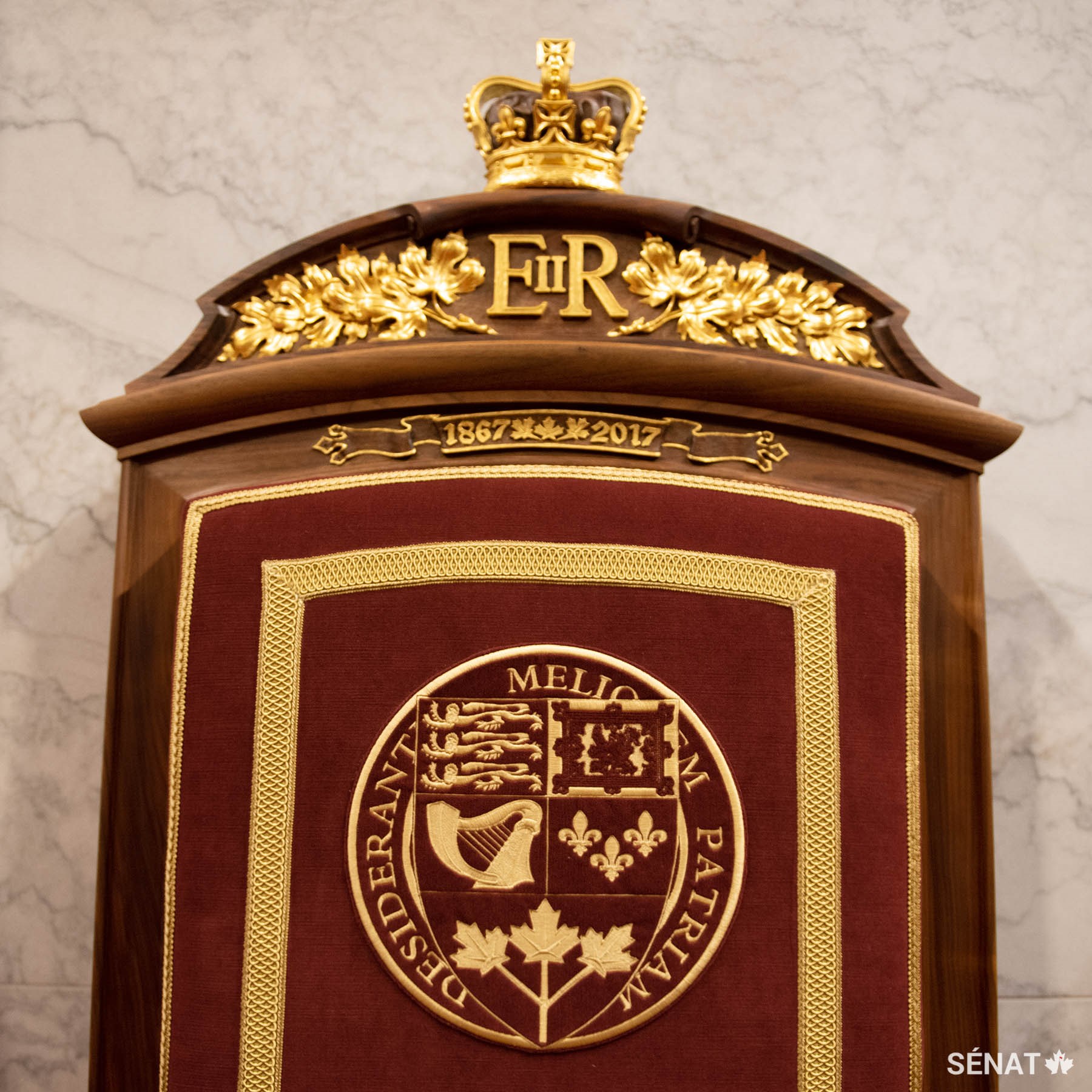 La tête des fauteuils intègre du noyer commun, qui provient du domaine du château de Windsor. Le monogramme de la Reine a été sculpté dans le trône du monarque; il est entouré de feuilles d’érable et surmonté de la couronne de saint Édouard.