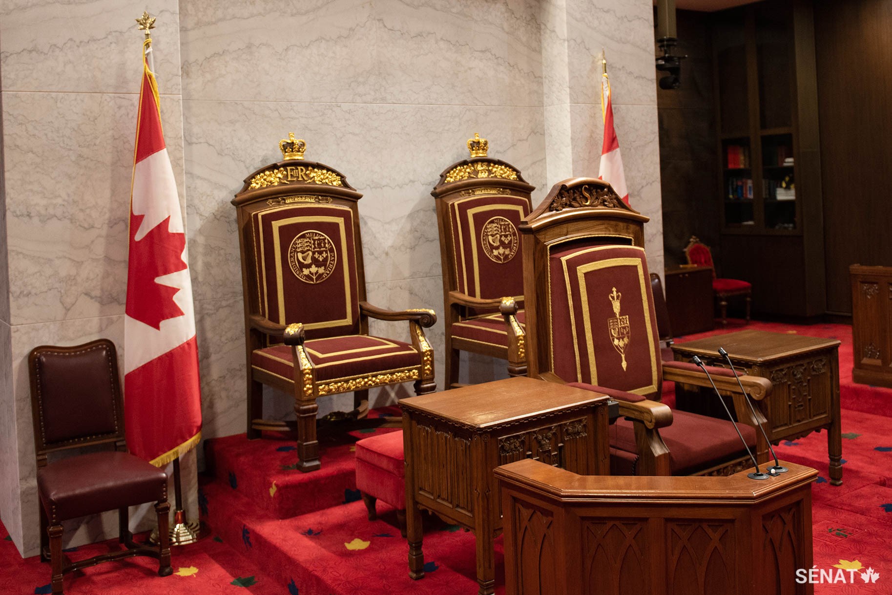 Les trônes du Canada et le fauteuil du Président du Sénat se trouvent sur une estrade située à l’avant de la Chambre du Sénat, dans l’édifice du Sénat du Canada.