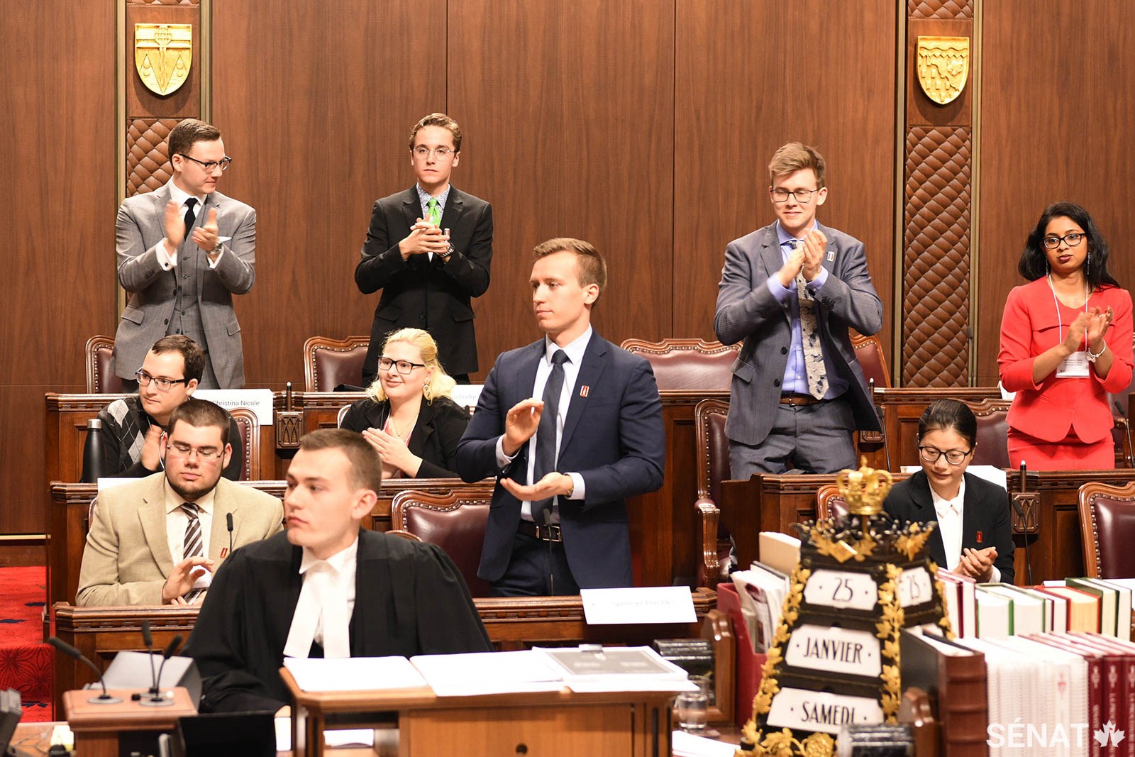 Des participants qui personnifient des sénateurs applaudissent l’intervention d’un collègue pendant une séance de la simulation du Sénat.