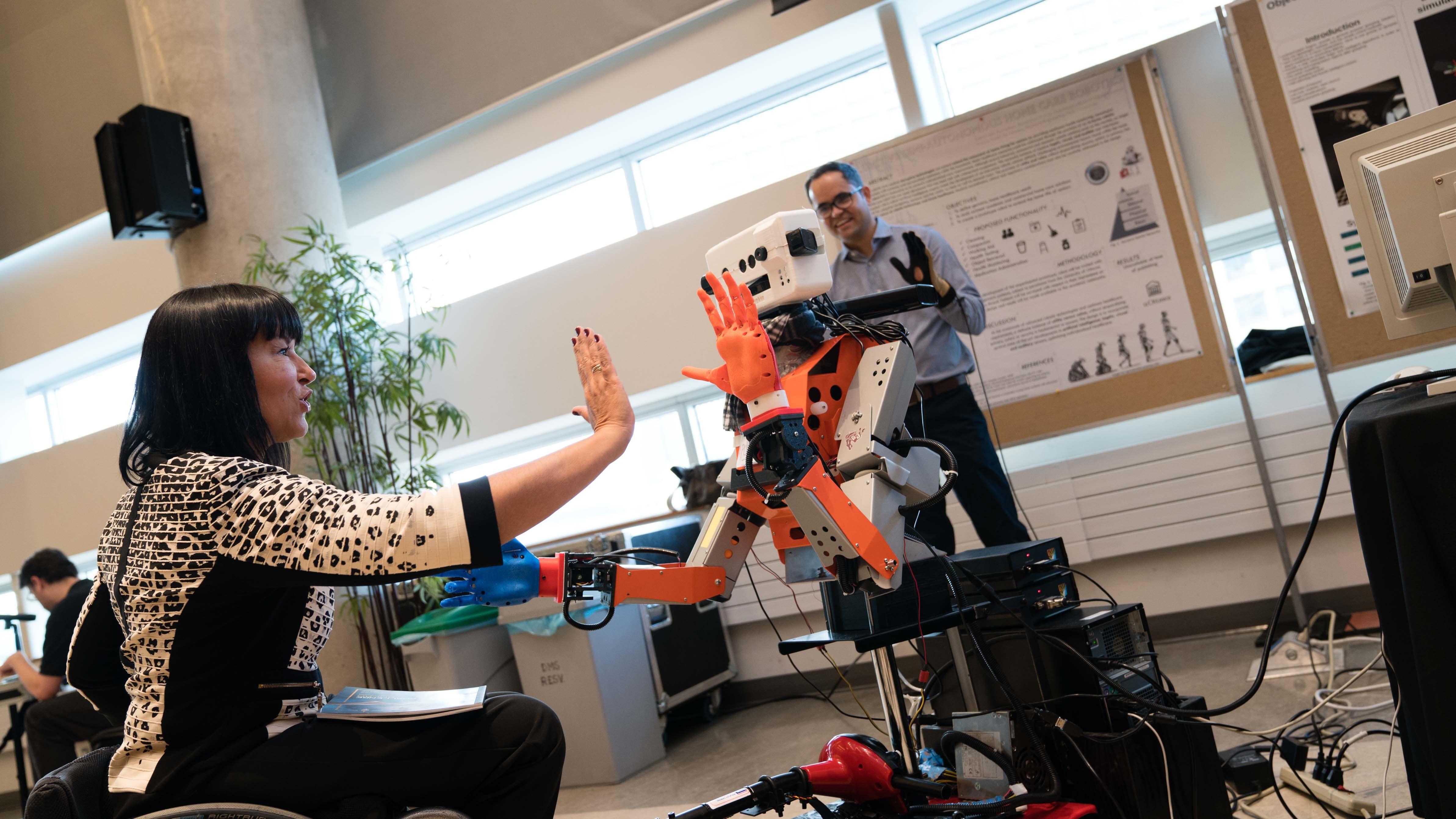 Senator Chantal Petitclerc high-fives a robot during an innovation fair in 2017 as part of her work on the Senate Committee on Social Affairs, Science and Technology.